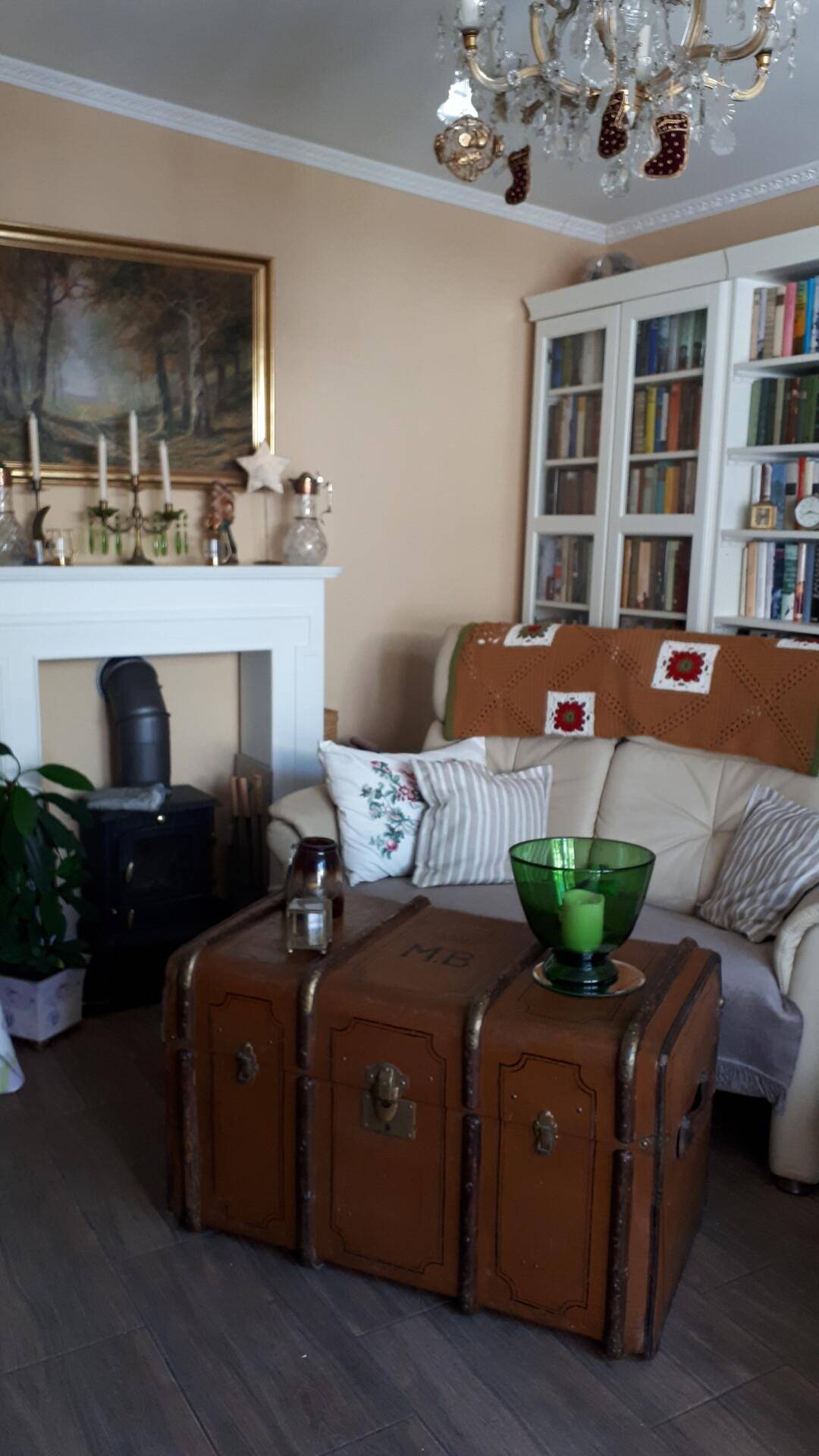 Wohnzimmer mit Kamin, Ledersofa und einem antiken Truhentisch als Couchtisch.