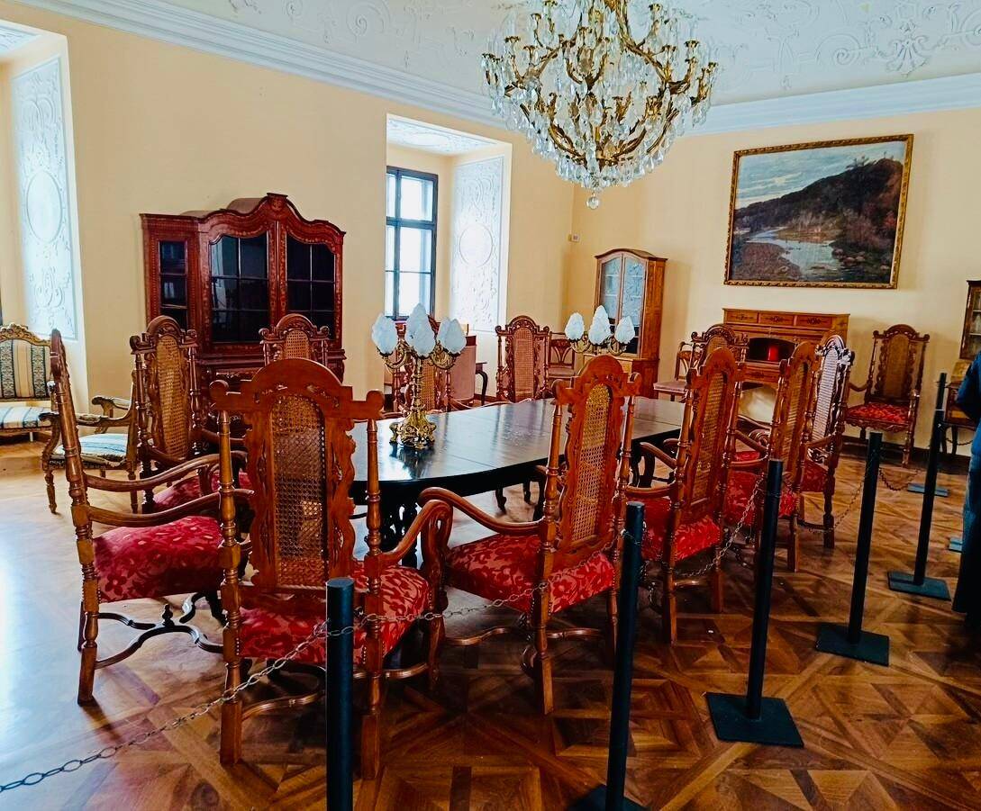Eleganter Speisesaal mit einem großen Holztisch, passenden Stühlen und einem opulenten Kronleuchter.