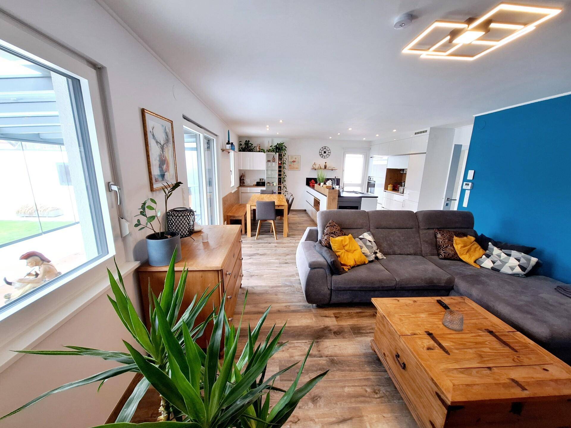 Heller offener Wohn- und Essbereich mit Holzboden, bequemer Couch und moderner Beleuchtung.