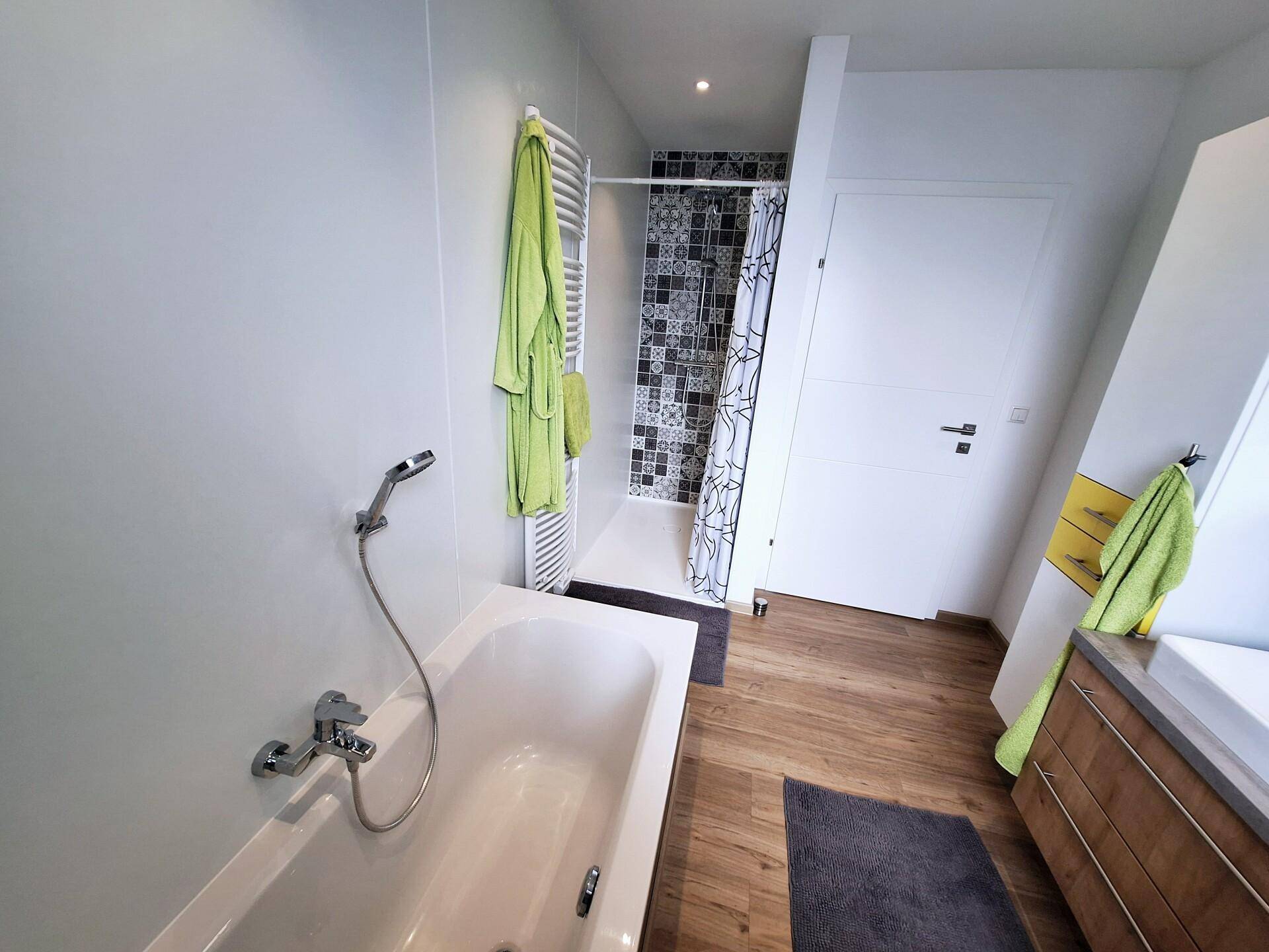Modernes Badezimmer mit Badewanne, Duschbereich und beheiztem Handtuchhalter.