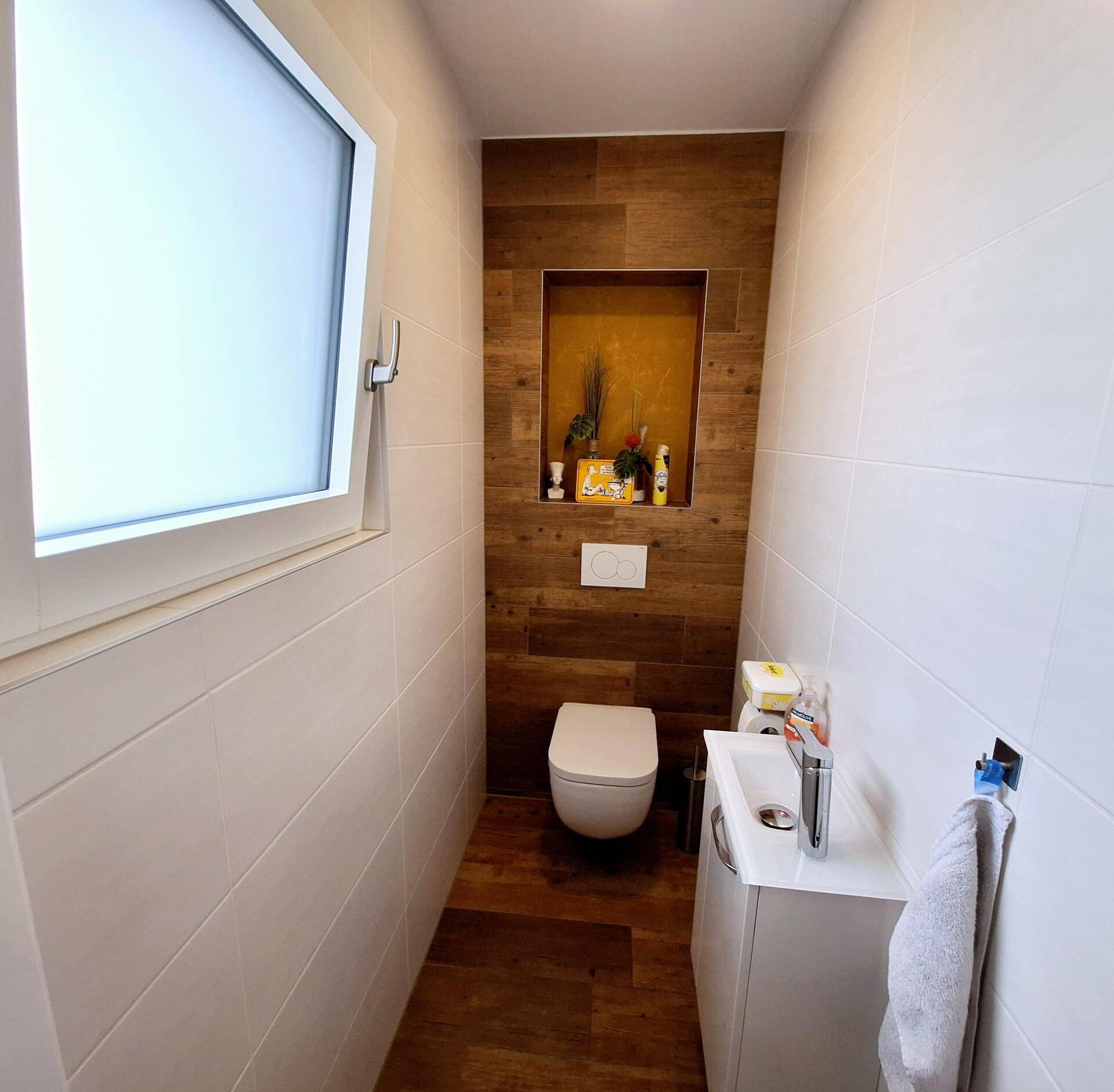 Modernes Gäste-WC mit wandhängendem WC, kleinem Waschbecken und Fenster.