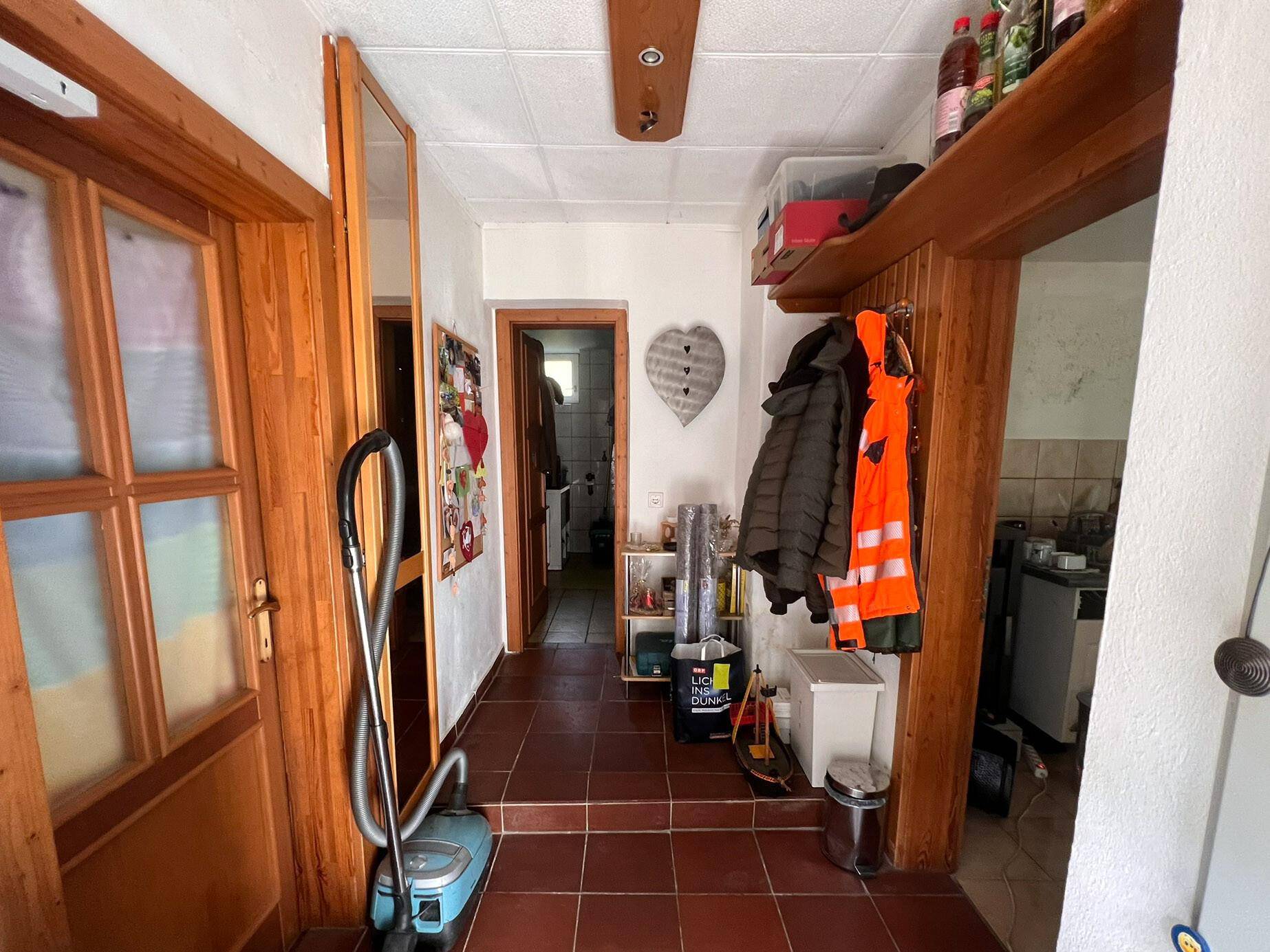 Flur mit Holztüren, Fliesenboden und Garderobe, der zu weiteren Räumen führt.