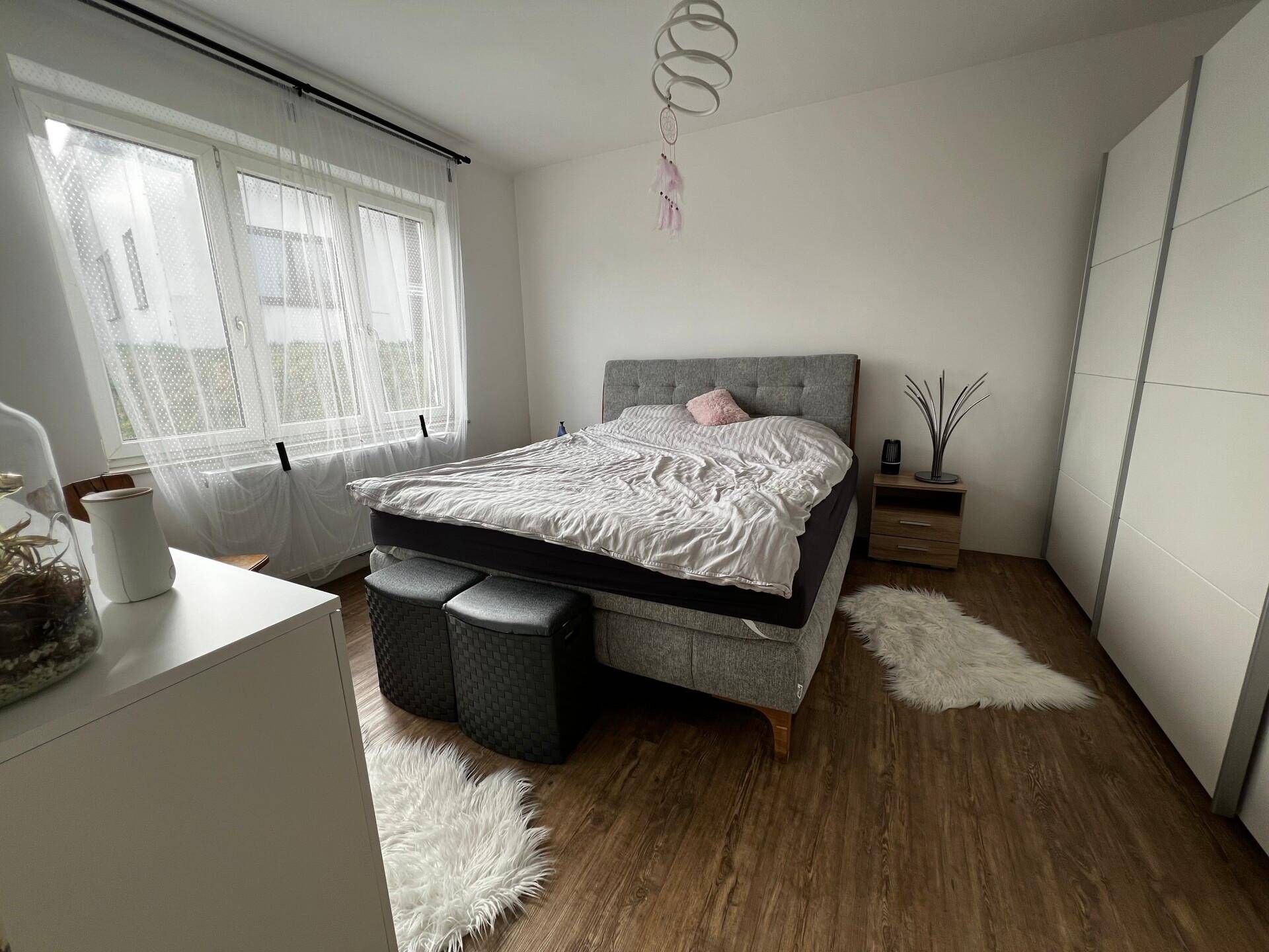 Helles Schlafzimmer mit Doppelbett, Nachttischen und großem Fenster für viel Tageslicht.