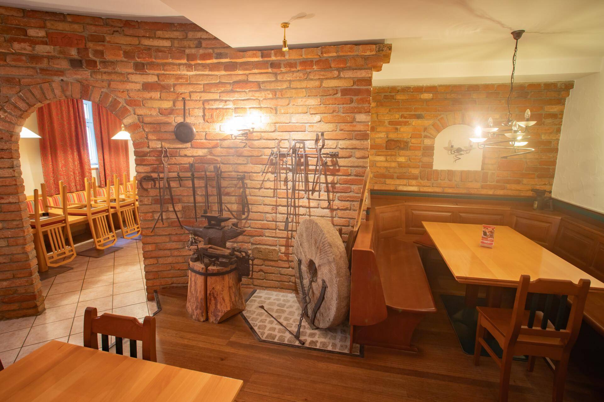 Gemütlicher Essbereich mit Ziegelwand, Holzboden und traditionellen Sitzgelegenheiten, ideal für rustikales Ambiente.