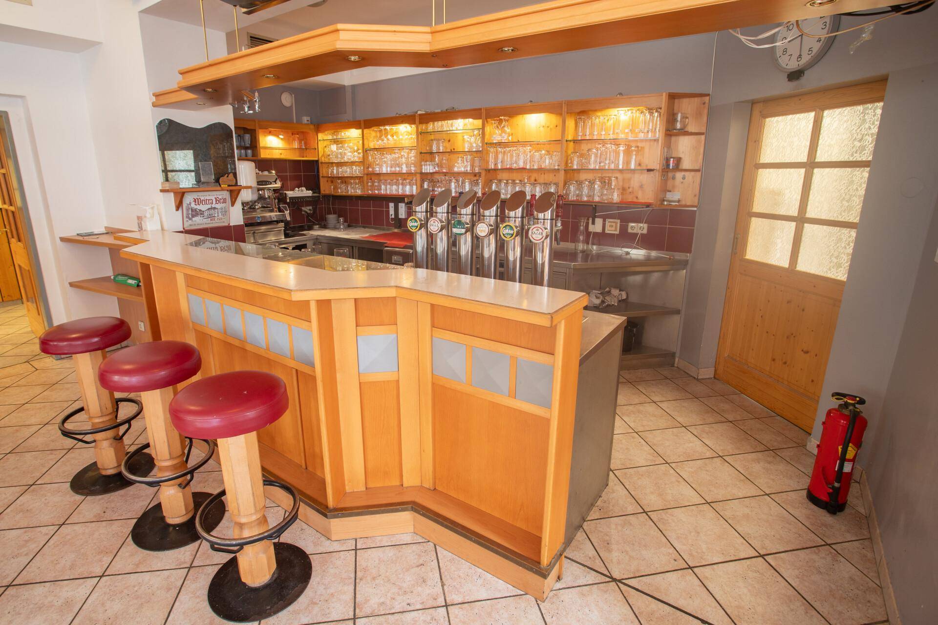 Traditionelle Bar mit Holzelementen, Zapfanlage und Barhockern, bereit für den Ausschank von Getränken.