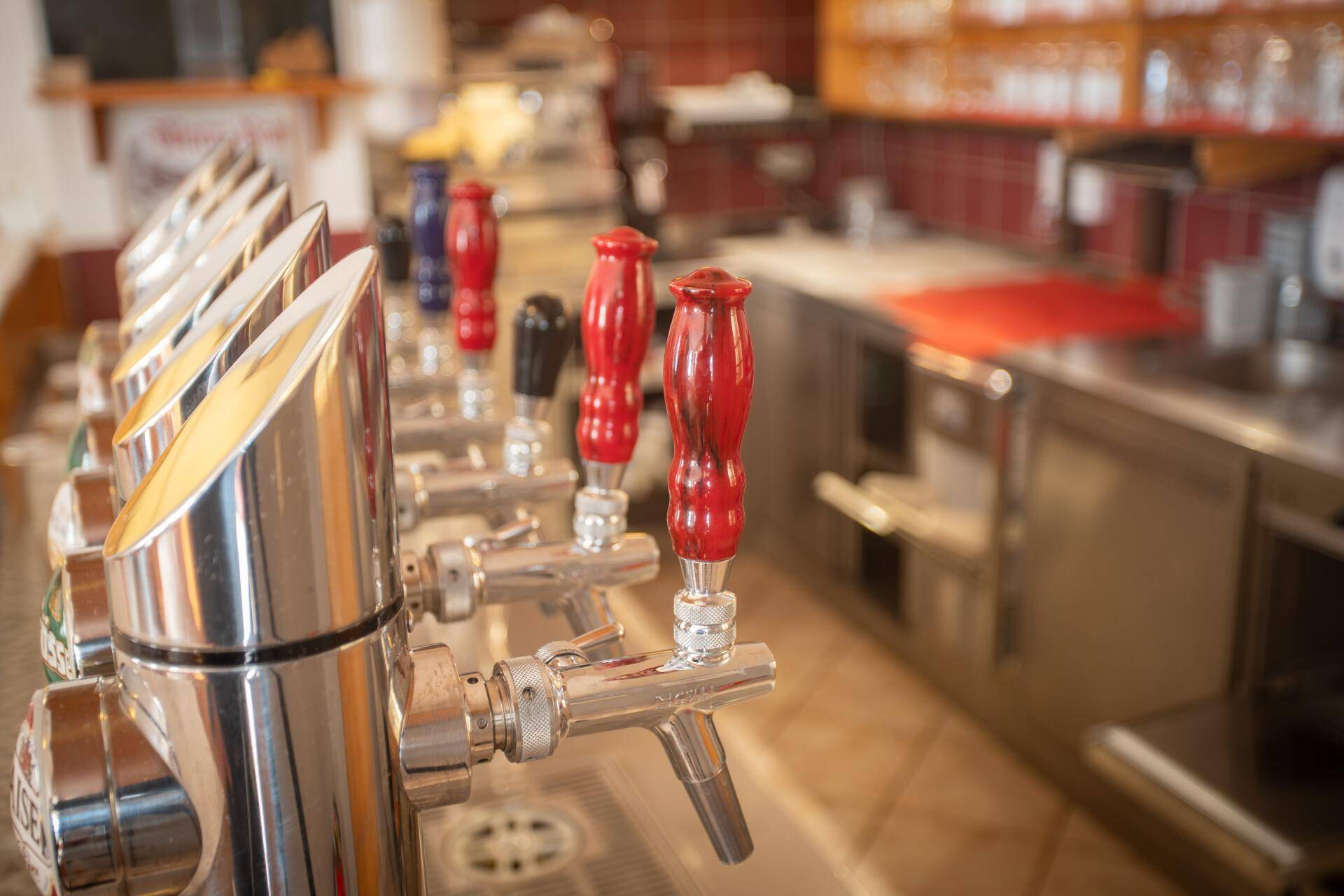 Nahaufnahme der glänzenden Zapfanlage mit roten Griffen, bereit für den Bierausschank in der Bar.