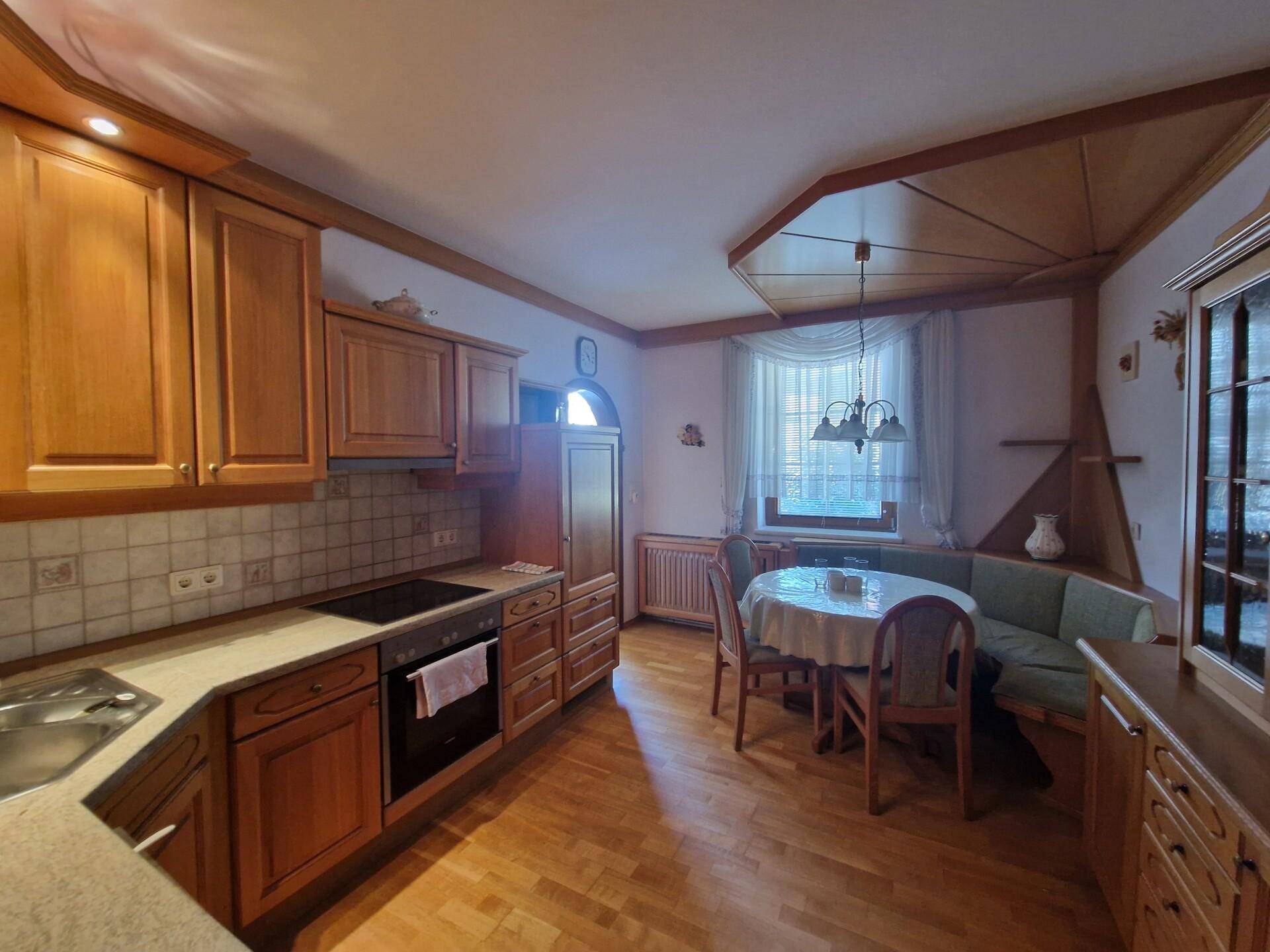 Gemütliche Wohnküche mit Holzschränken, Essbereich und traditioneller Holzdecke.