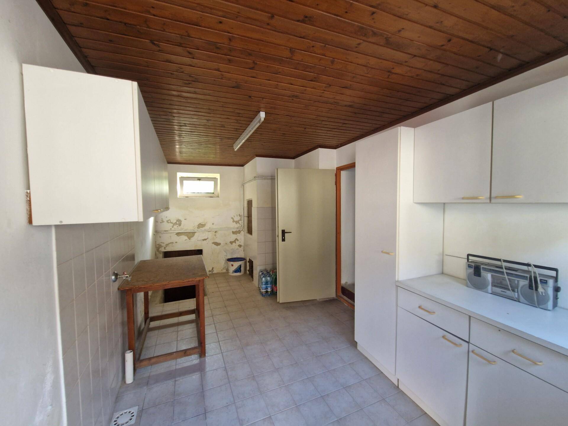 Kellerraum mit Holzdecke, einfachen Schränken und sichtbaren Abnutzungsspuren.