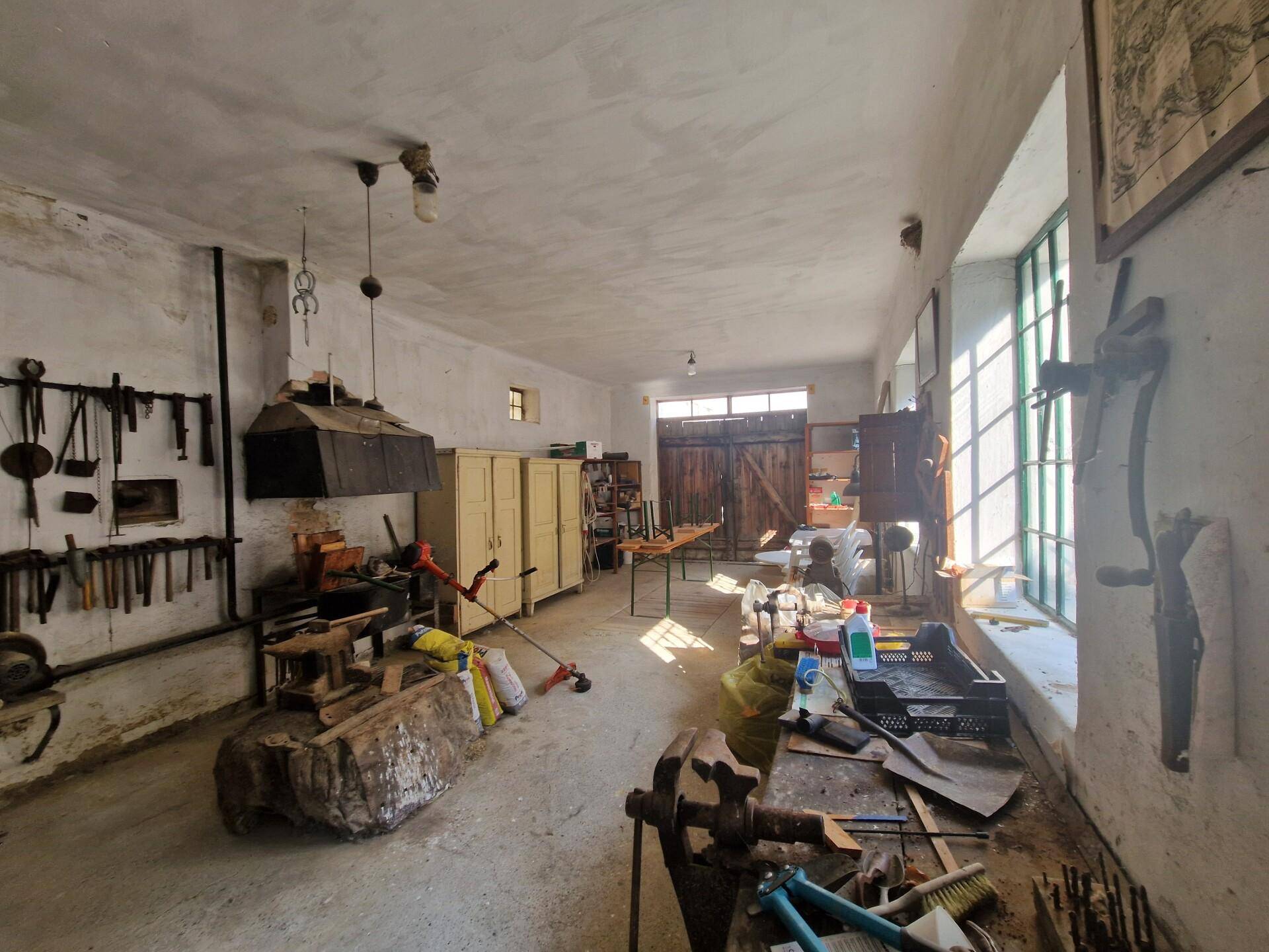 Große Werkstatt mit Werkzeugen, hohen Fenstern und viel Tageslicht.