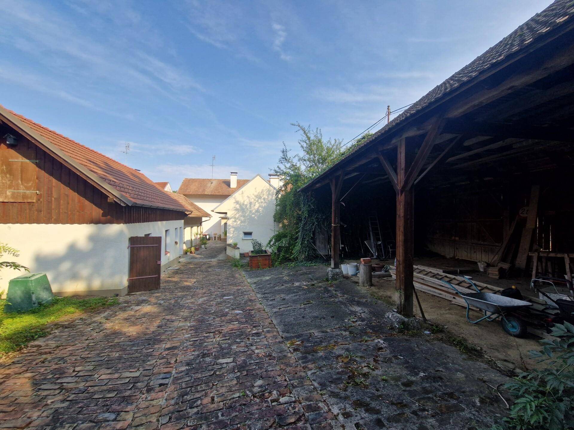 Gepflasterter Hof zwischen den Gebäuden mit einer Scheune im Hintergrund.