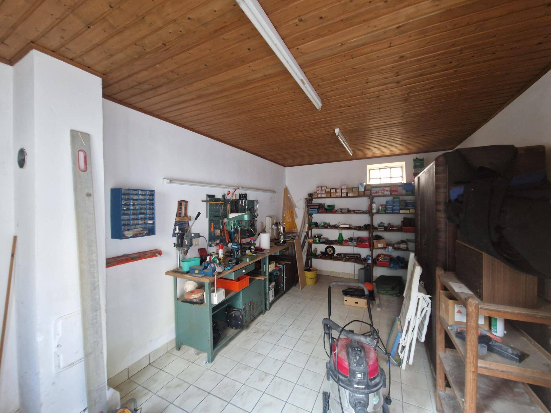 Werkstatt mit Werkbänken, Regalen und Holzdecke, gut ausgestattet für Handwerksarbeiten.
