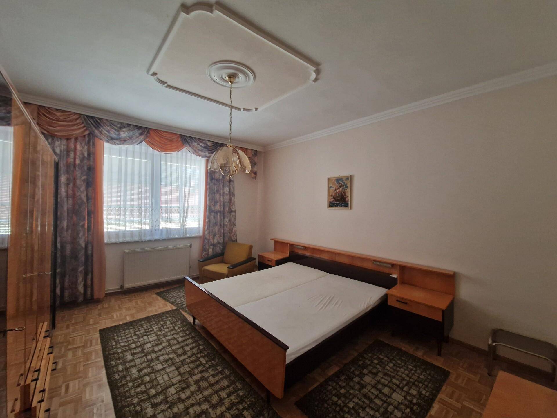 Schlafzimmer mit Holzdecke, Parkettboden und traditionellem Bettgestell.