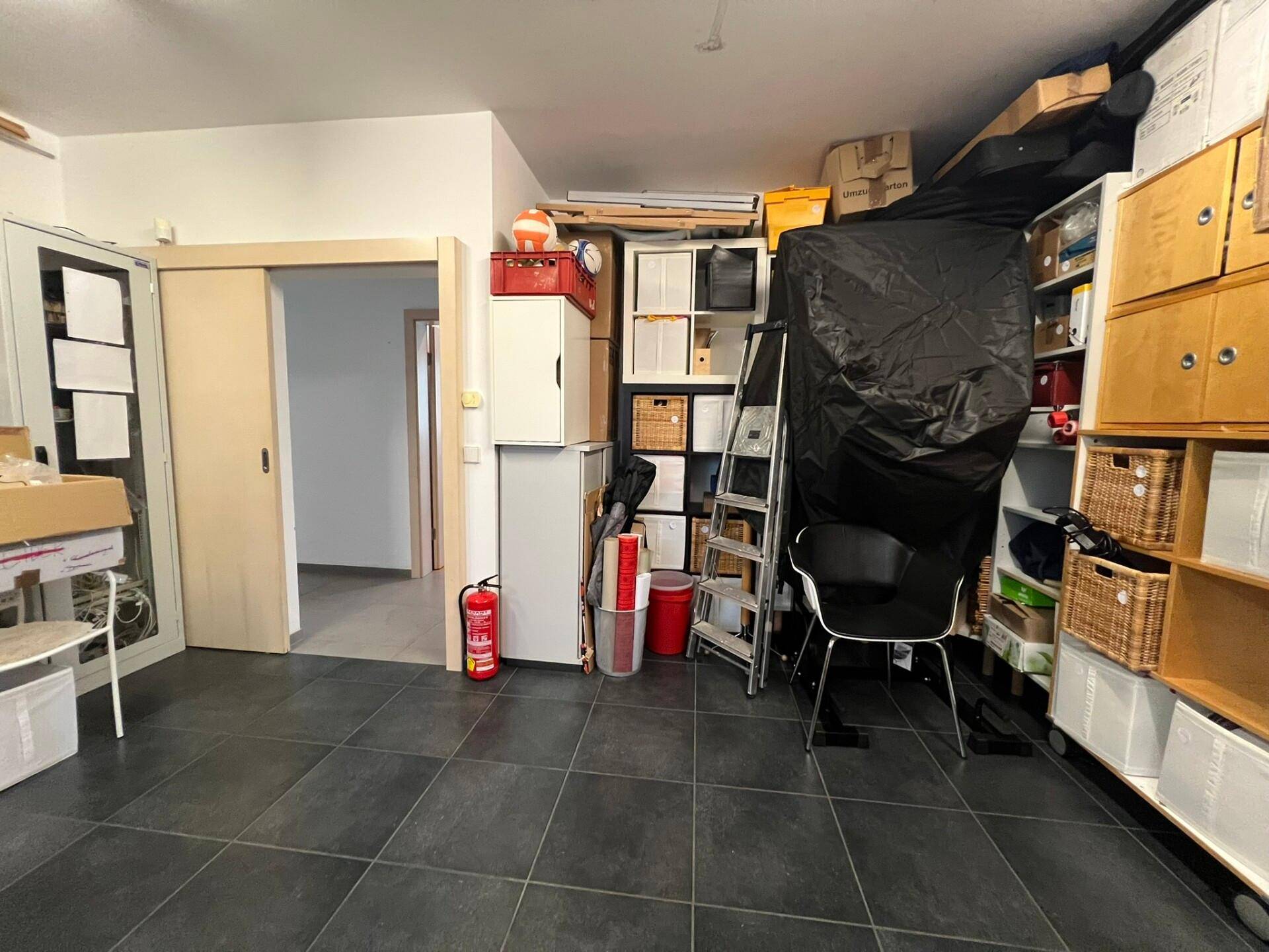 Organisiertes Lager mit Fliesenboden, Regalen und einem Feuerlöscher, bereit für den täglichen Gebrauch.