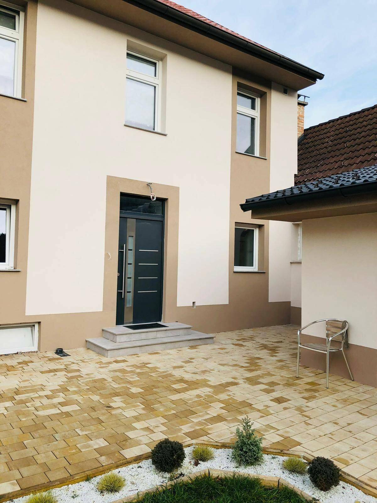 Eingangsbereich des Hauses mit moderner Haustür und gepflastertem Vorplatz.