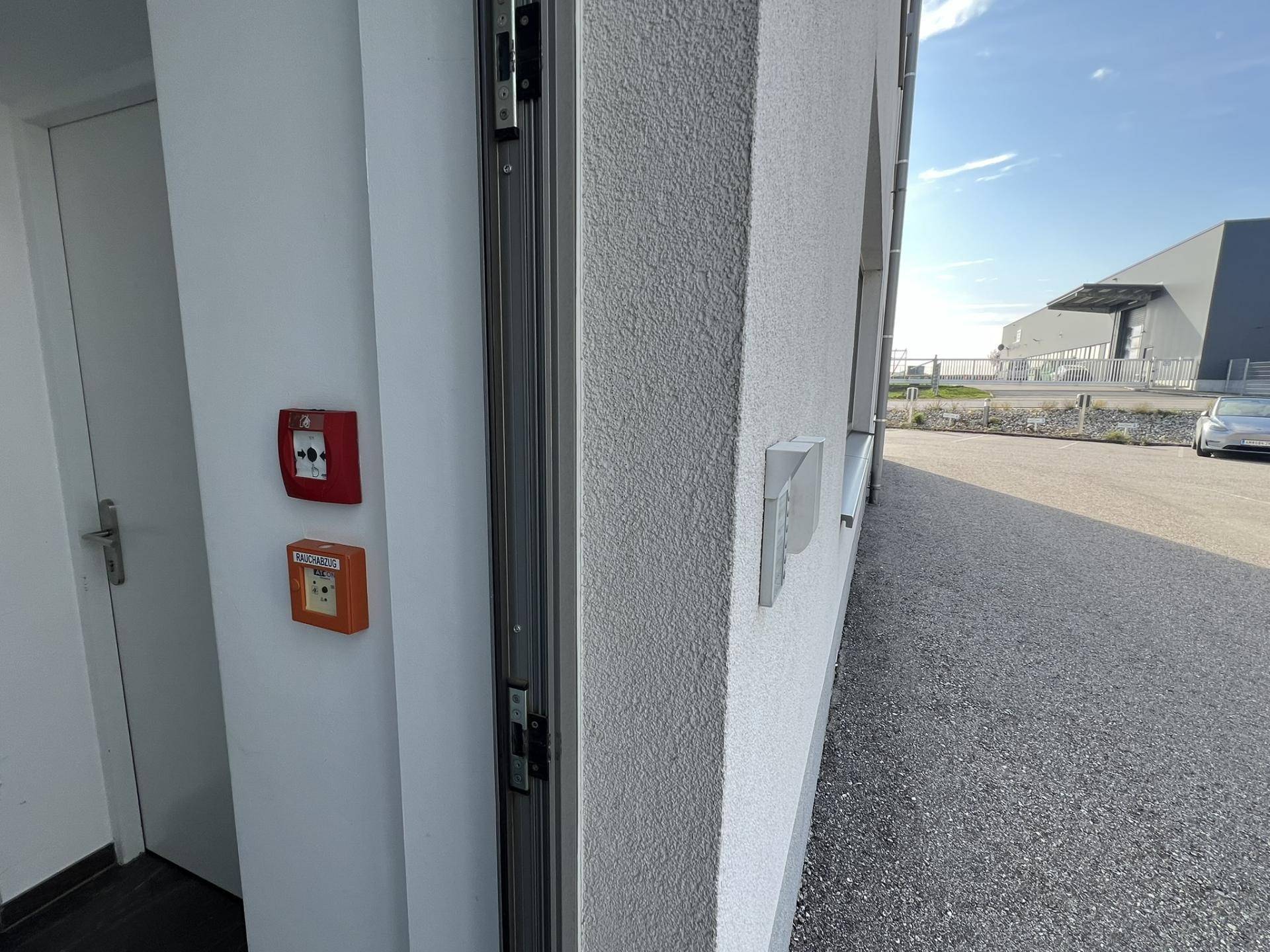 Detailansicht des Gebäudeeingangs mit Klingelanlage und Brandschutzschaltern an der Fassade, sicher und modern.