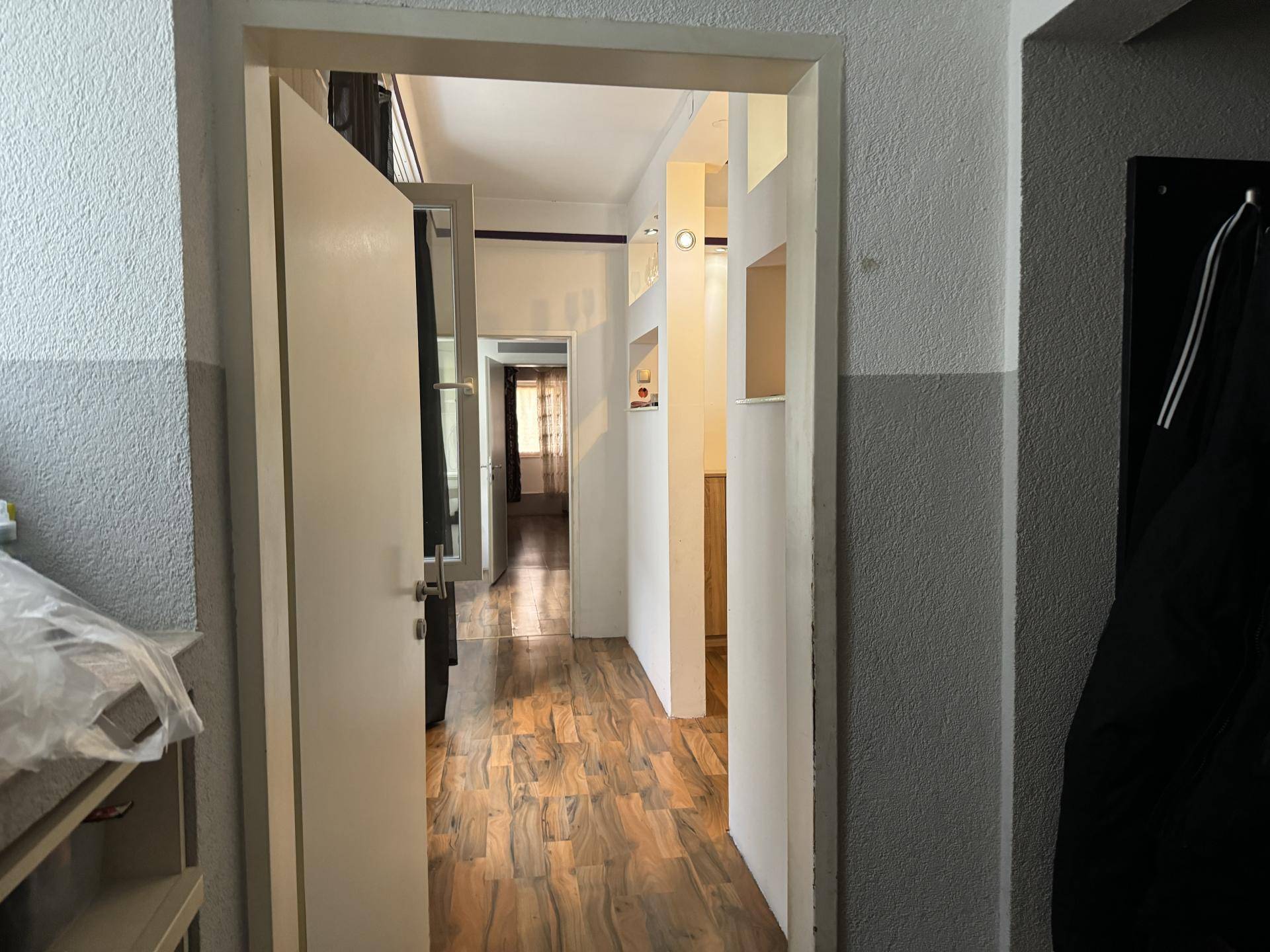 Langer Flur mit Holzboden und mehreren Türen, der verschiedene Räume verbindet.