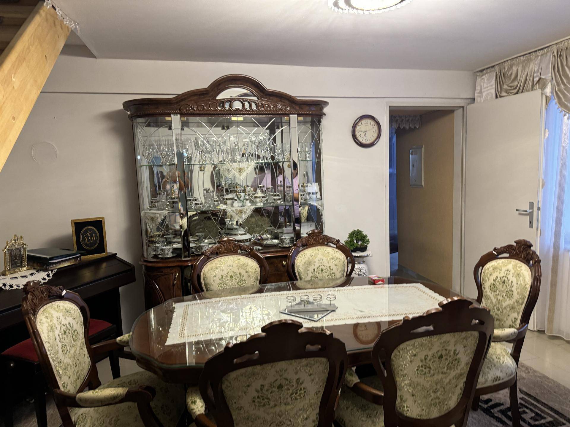 Klassischer Essbereich mit großem Holztisch, verzierten Stühlen und einem antiken Vitrinenschrank.