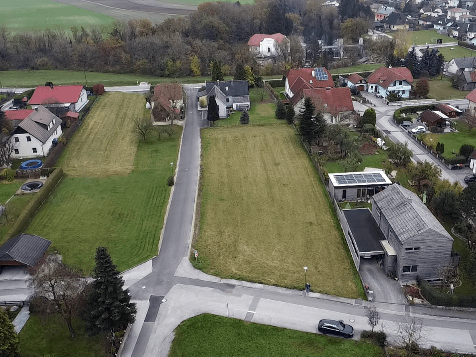 Weitläufige Luftaufnahme einer ländlichen Wohnsiedlung mit Einfamilienhäusern und großen Grünflächen.