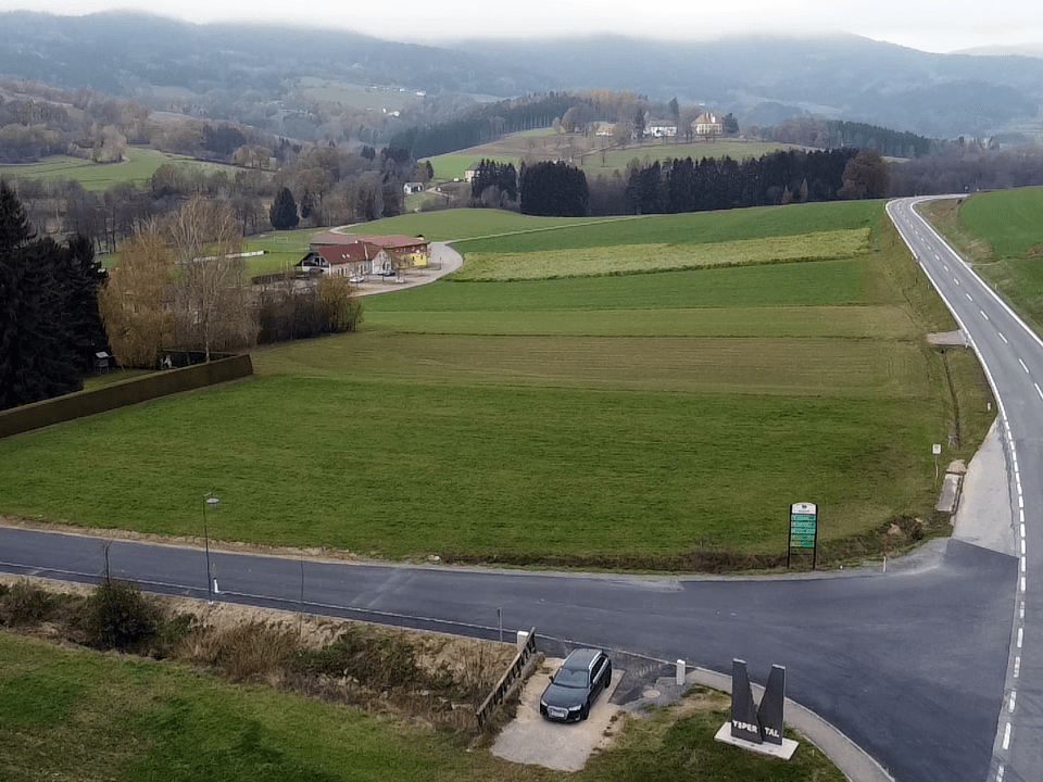 Luftaufnahme einer ländlichen Gegend mit grünen Feldern, einer Straße und einem Denkmal, umgeben von Hügeln.
