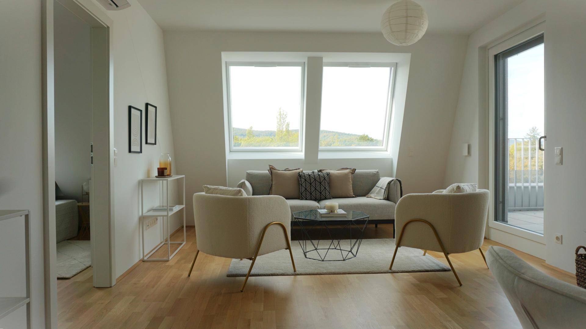 Lichtdurchflutetes Wohnzimmer mit Dachfenstern, Holzboden und direktem Zugang zur Terrasse.