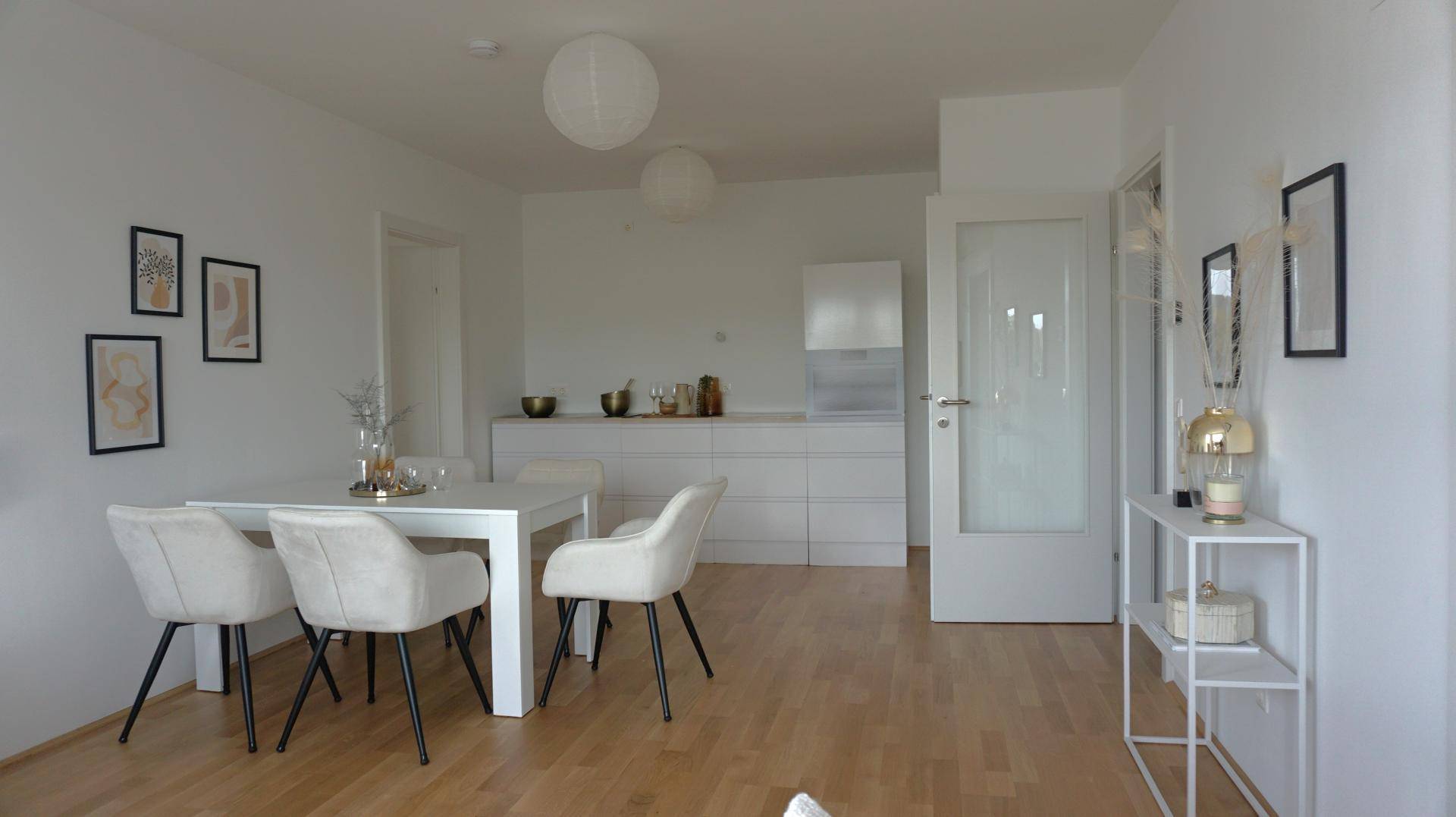 Moderner Essbereich mit angrenzender, minimalistischer Einbauküche und hellem Holzboden.