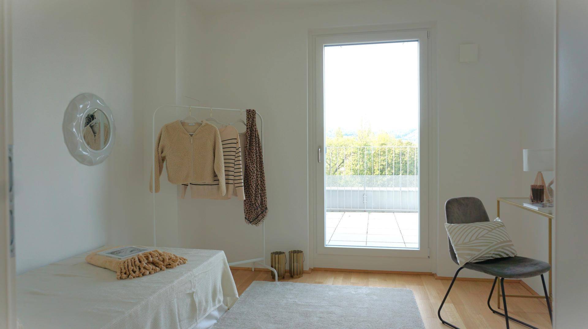 Helles Schlafzimmer mit direktem Zugang zur Terrasse und schlichter, moderner Einrichtung.