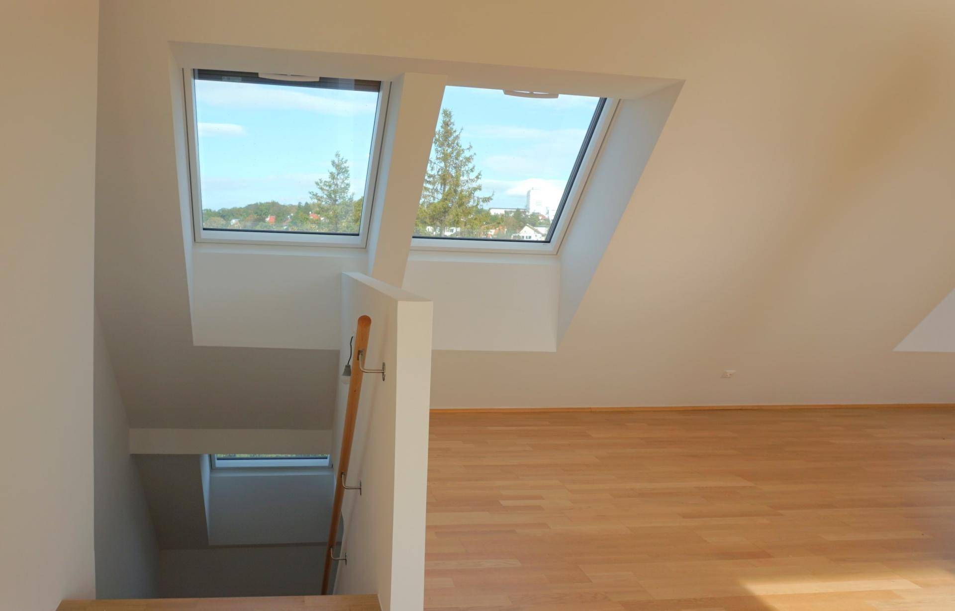 Treppenabsatz mit Holzfußboden und Dachfenstern, die viel Licht hereinlassen.