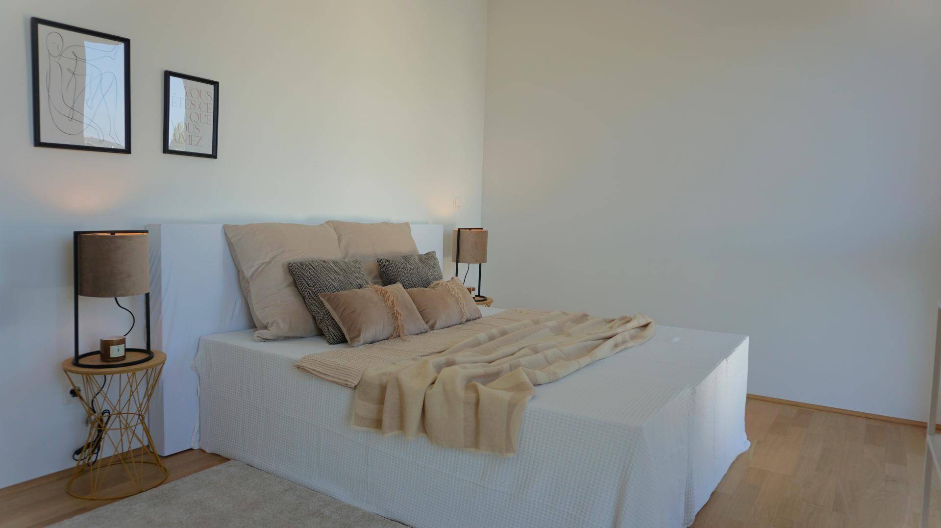 Schlafzimmer mit hellem Holzboden, minimalistischer Einrichtung und bequemen Bett.
