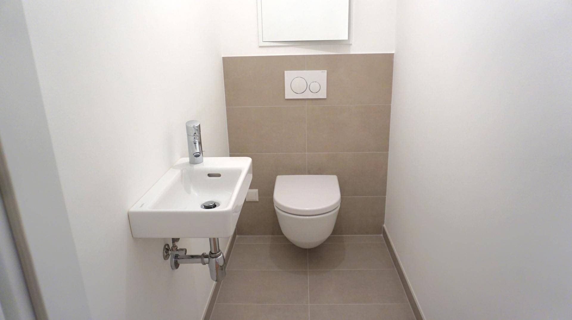 Kleines Gäste-WC mit wandhängender Toilette und modernem Waschbecken, sauber und funktional.