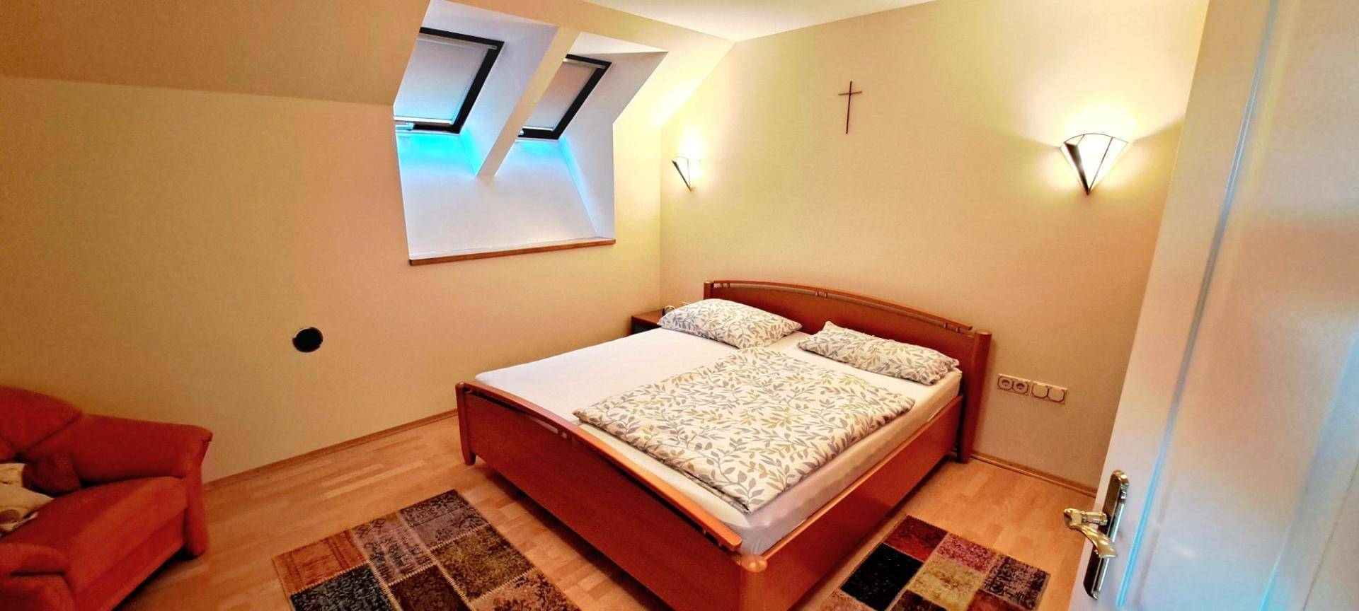 Gemütliches Schlafzimmer im Dachgeschoss mit Holzbett, Parkettboden und Dachfenstern.