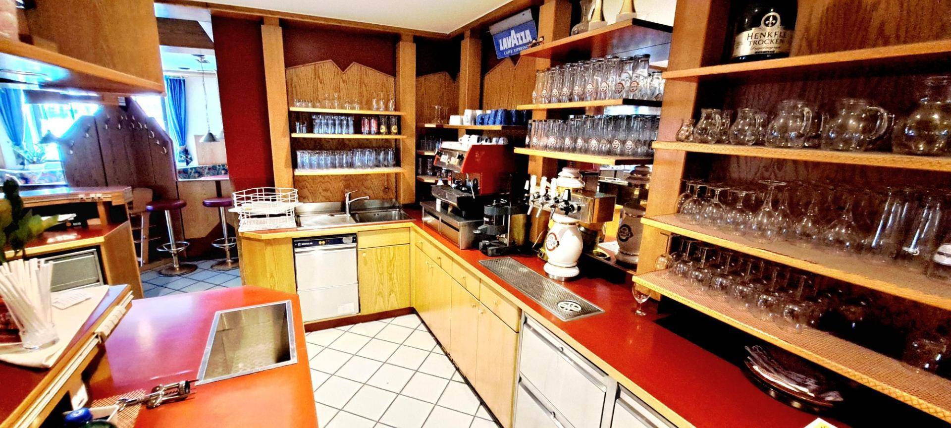 Professionelle Großküche mit Edelstahlgeräten, roten Arbeitsflächen und Fliesenwänden.