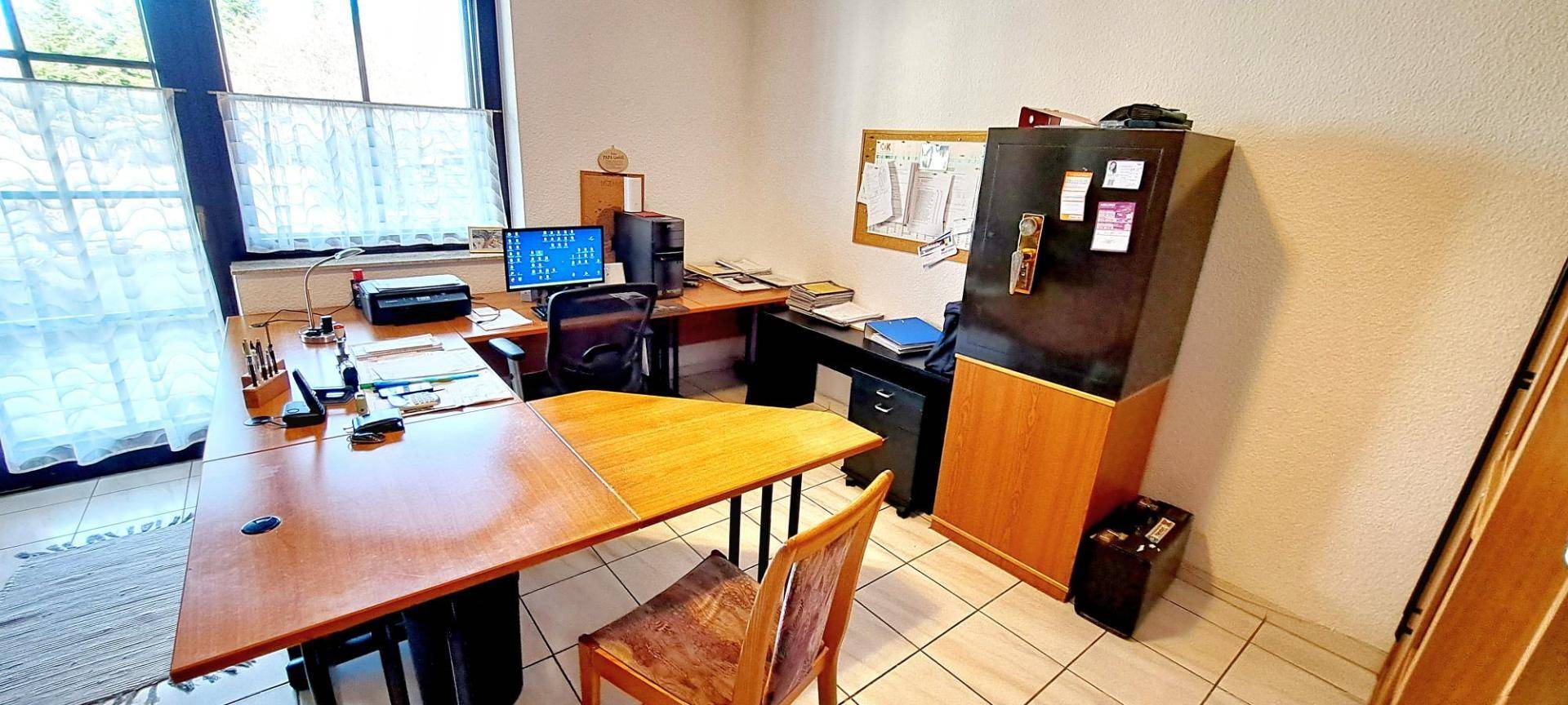 Funktionales Büro mit großem Schreibtisch, Bürostuhl und Blick ins Grüne.