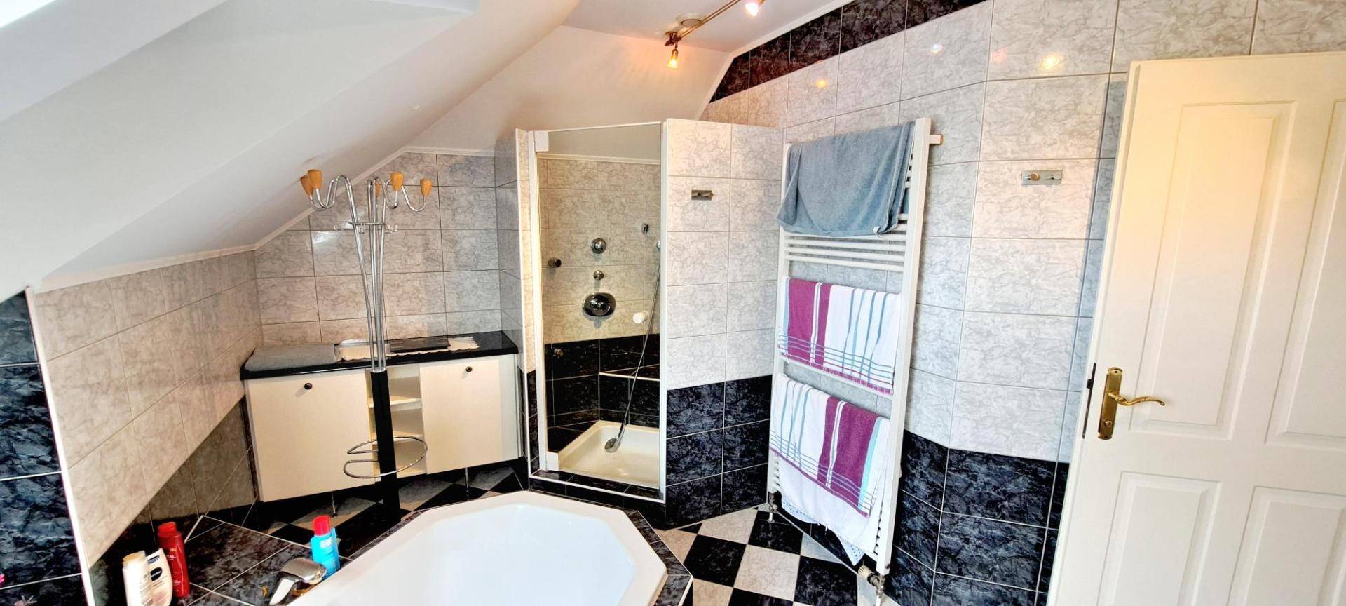 Helles Badezimmer im Dachgeschoss mit Dusche, Badewanne und beheiztem Handtuchhalter.