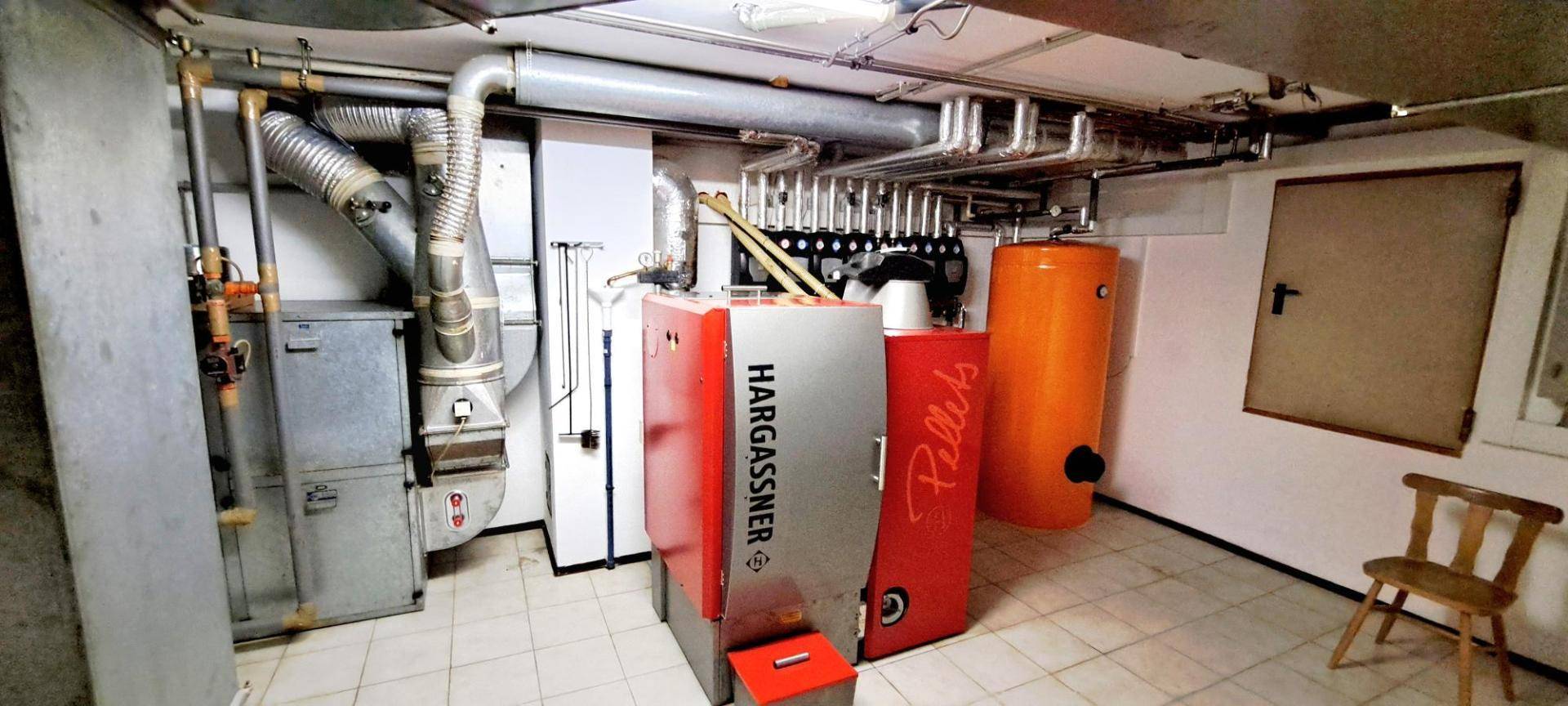 Heizungsraum im Keller mit moderner Pelletheizung und Warmwasserspeicher.