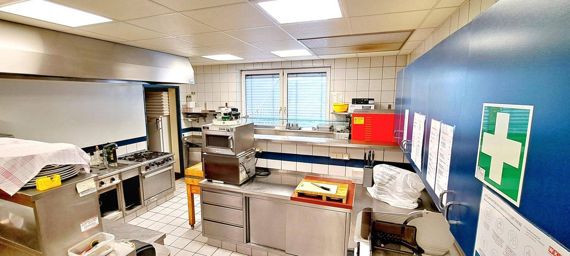 Gut ausgestattete Gewerbeküche mit professionellen Geräten und funktionalen Arbeitsbereichen.