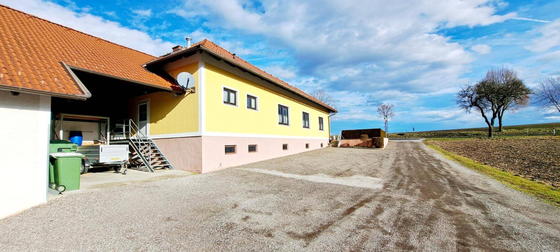 Seitenansicht des Hauses mit Zufahrt und angrenzendem Feld.