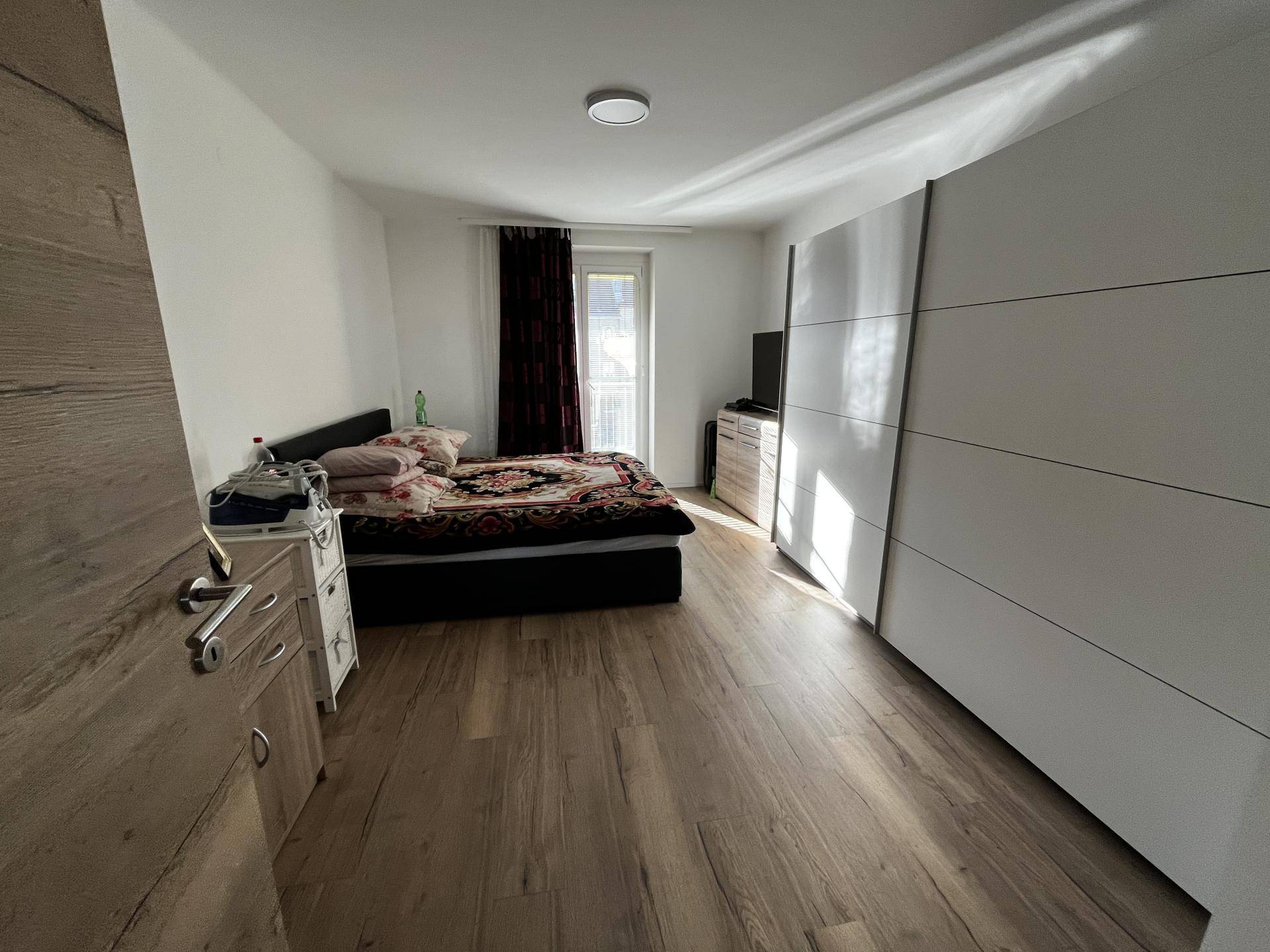 Schlafzimmer mit Doppelbett, großem Kleiderschrank und Zugang zu einem französischen Balkon.