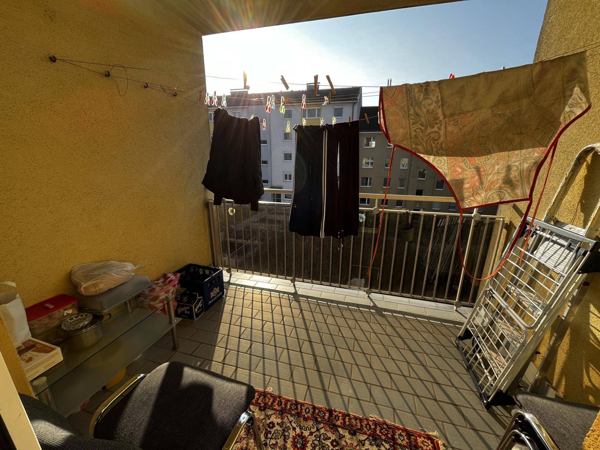 Sonniger Balkon mit Wäscheleine und Blick auf die umliegenden Gebäude.