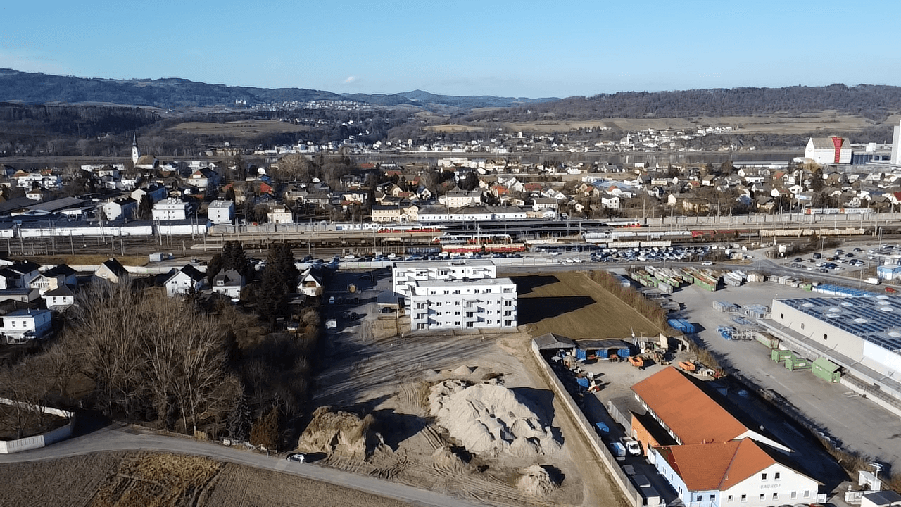 Panoramablick aus der Luft auf eine Stadt mit Industriegebiet, Wohngebäuden und weiten Feldern.