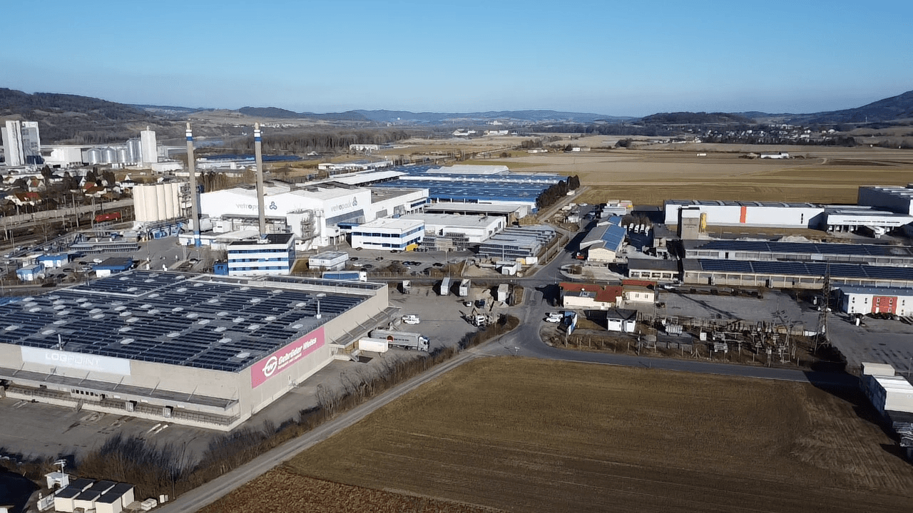 Panoramablick aus der Luft auf ein großes Industriegebiet mit vielen Gebäuden und Solaranlagen auf den Dächern.