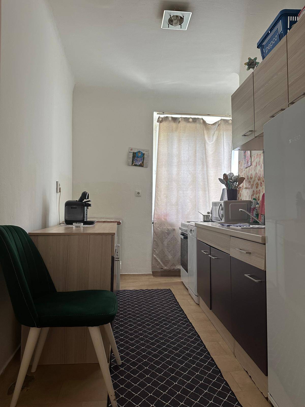 Kleine, funktionale Küche mit Einbauschränken, Fenster und grundlegenden Geräten.