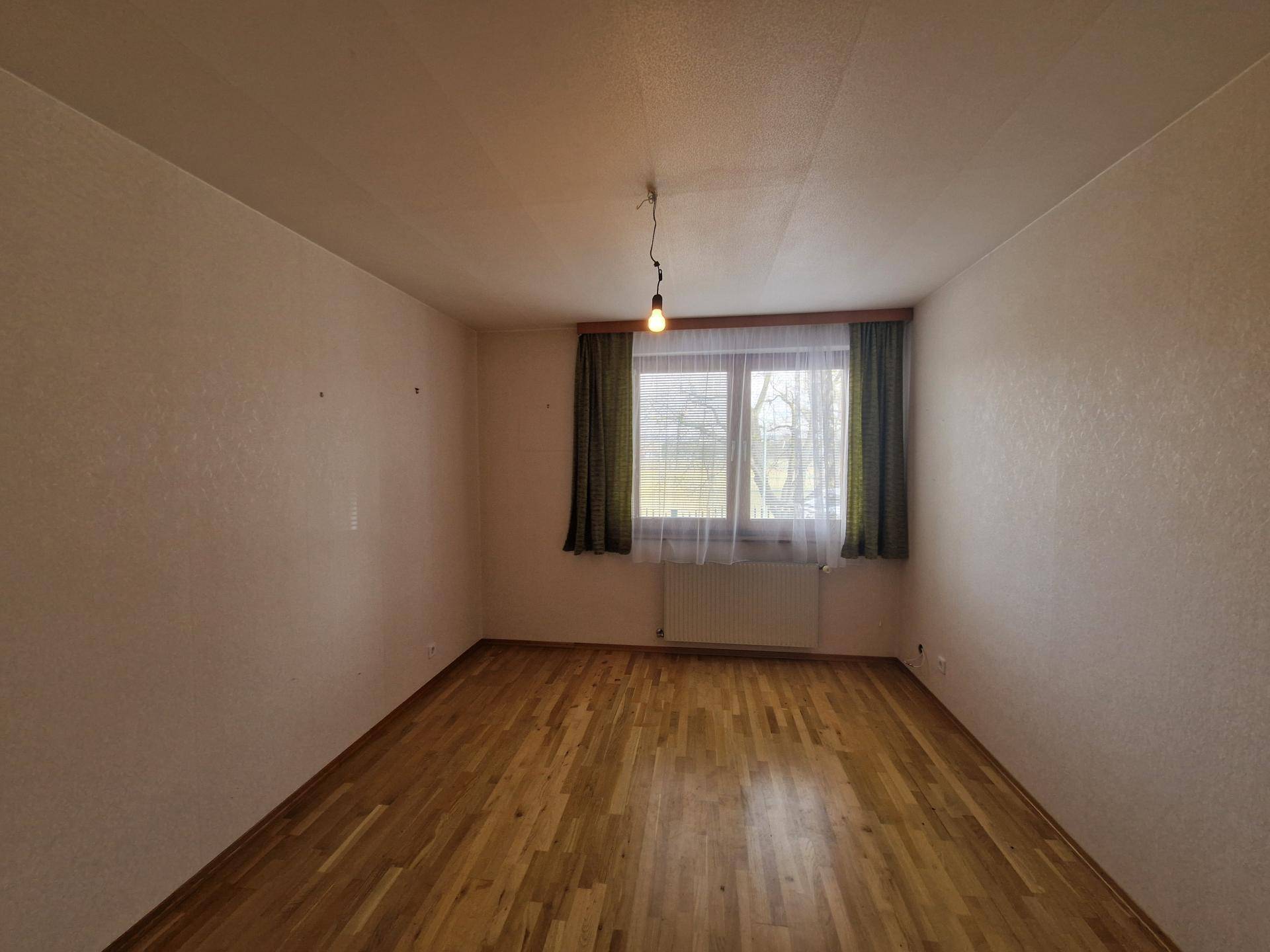 Schlafzimmer mit Parkettboden und Fenster mit Blick auf die ländliche Umgebung.