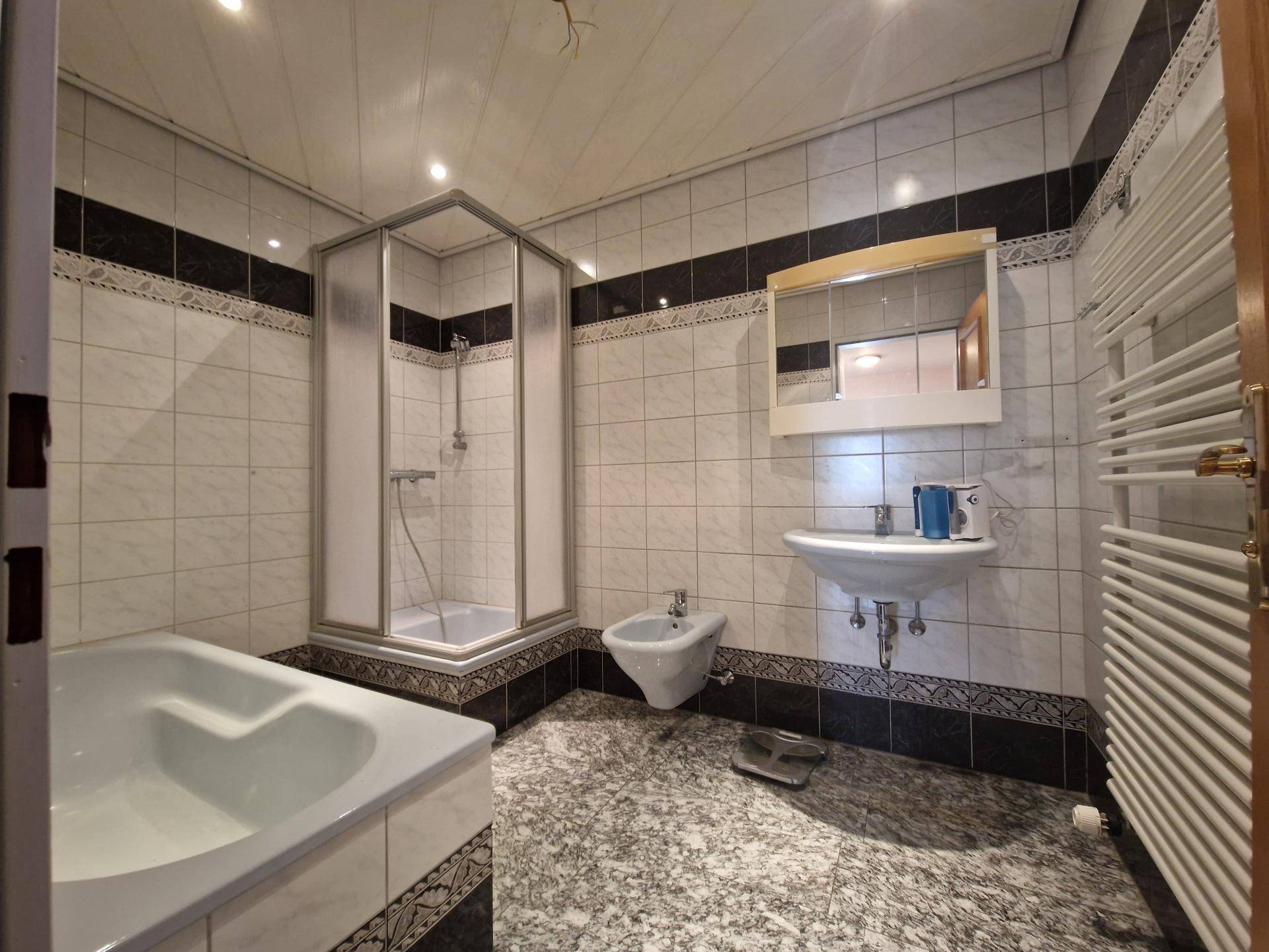Gefliestes Badezimmer mit Badewanne, Dusche, Bidet und Einzelwaschbecken.