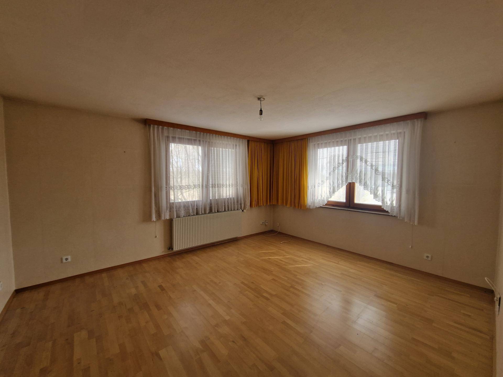 Helles Schlafzimmer mit Parkettboden und zwei Fenstern für gute Belichtung.