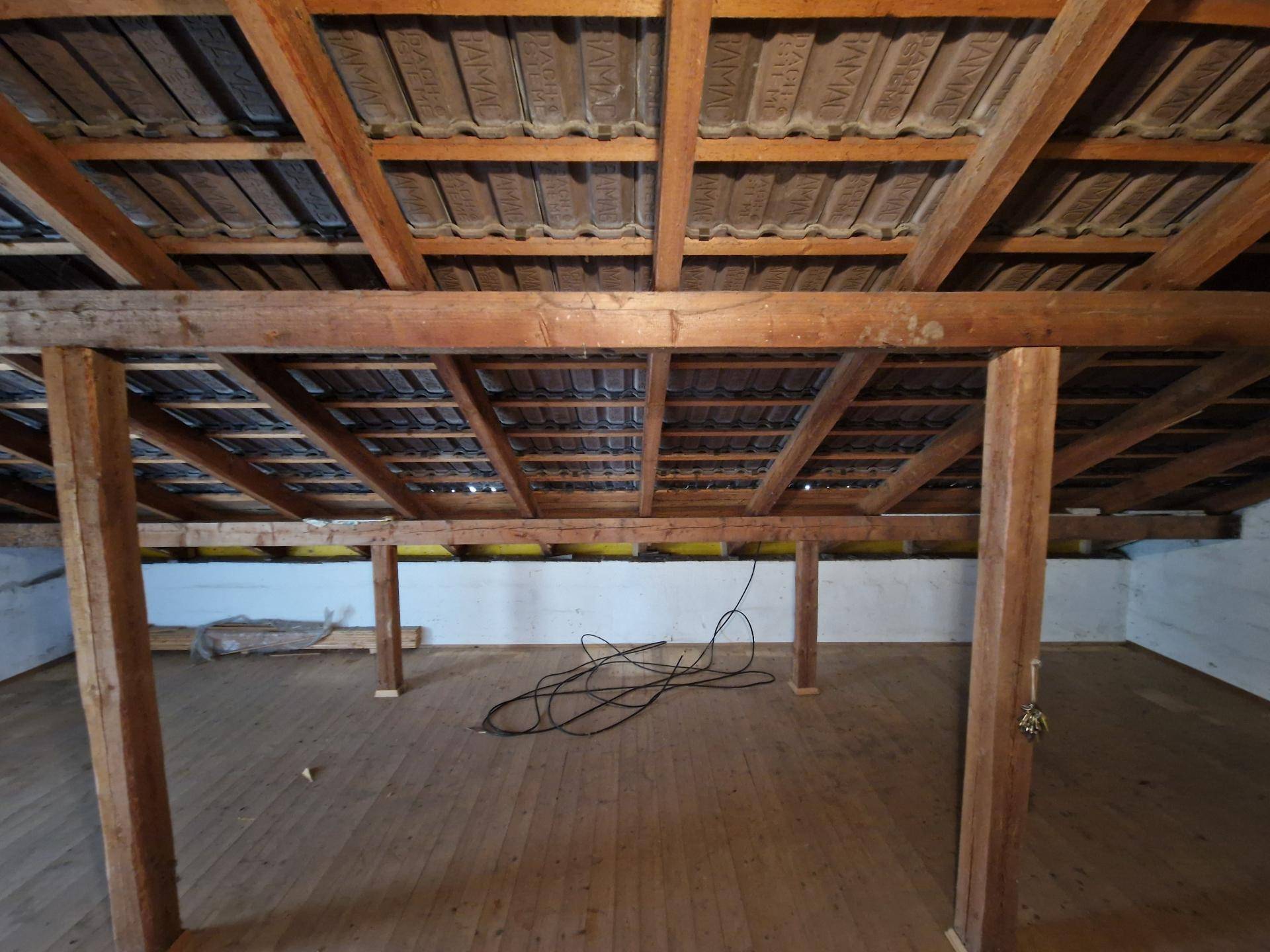 Großer Dachboden mit sichtbarer Dachkonstruktion und Holzdielenboden.