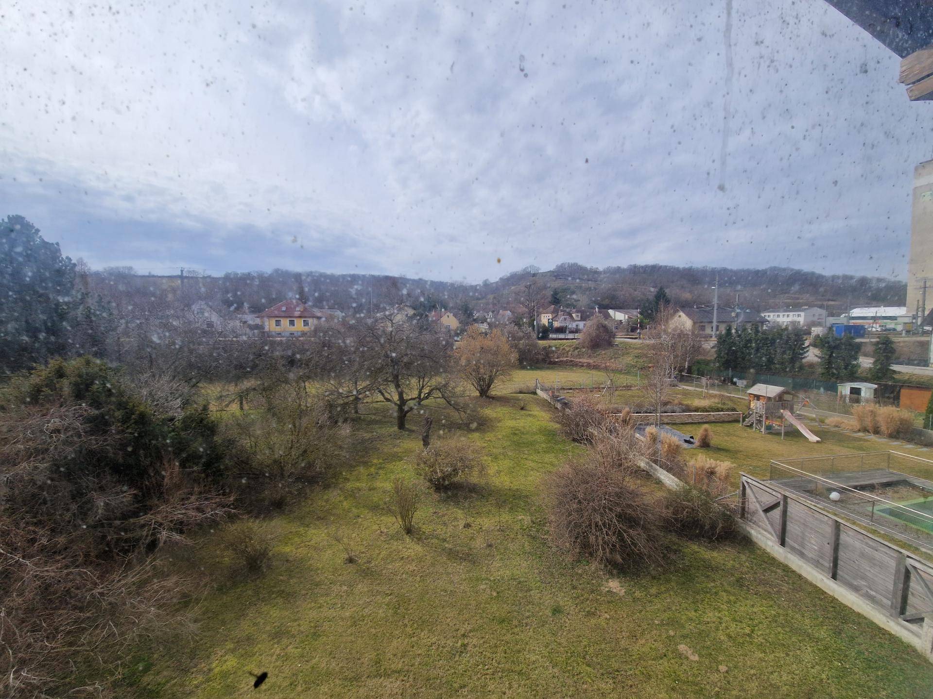 Weitläufiger Blick aus dem Fenster auf die grüne Umgebung und einen Spielplatz.