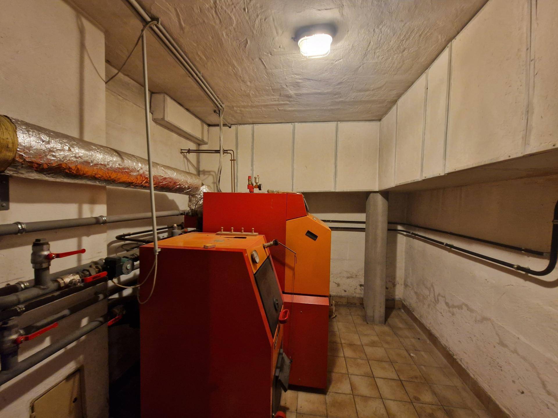 Heizungsraum im Keller mit großem Heizkessel und Rohrleitungen.