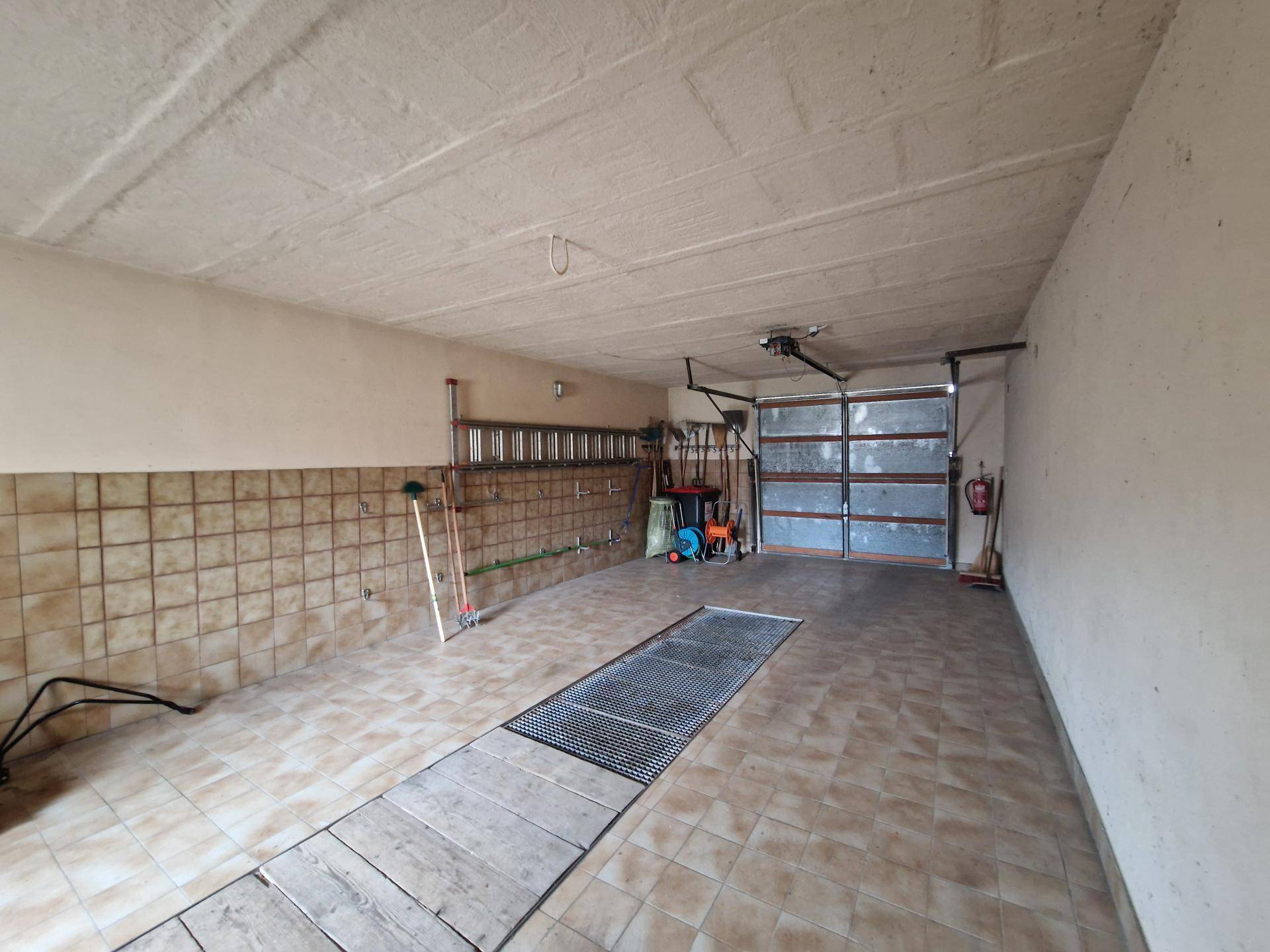 Geräumige Garage mit Fliesenboden und Rolltor.