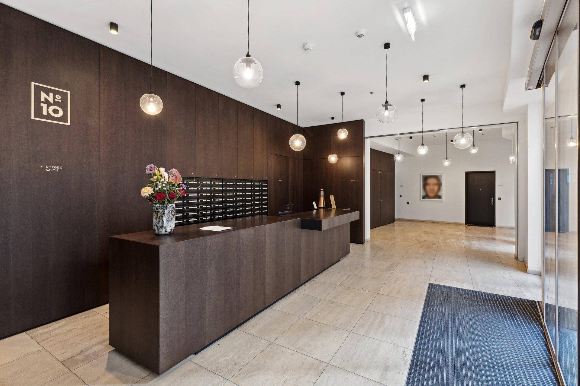 Elegante Lobby mit Rezeption, Briefkästen und stilvoller Beleuchtung.