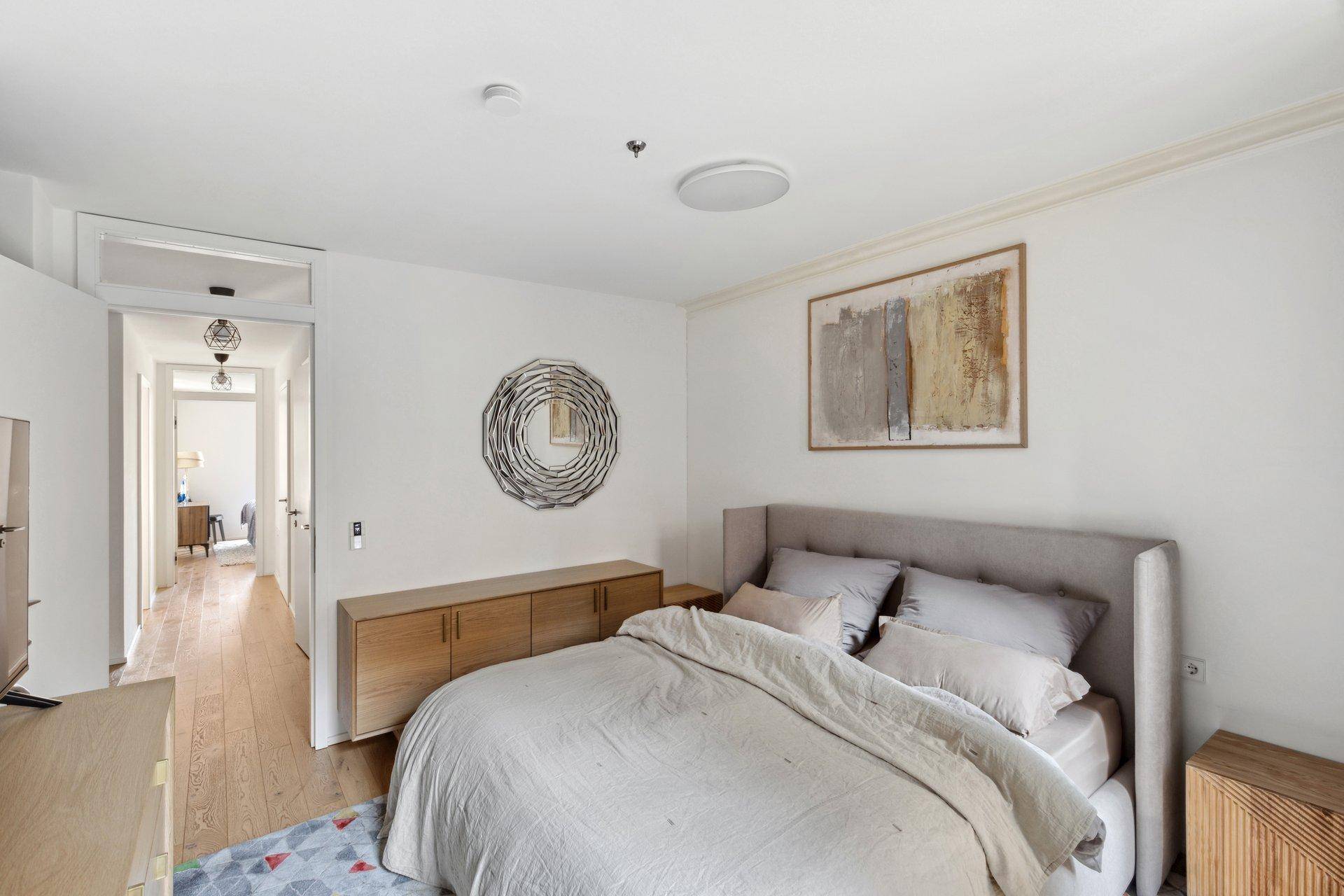 Modern eingerichtetes Schlafzimmer mit Holzboden und Kunst an der Wand.